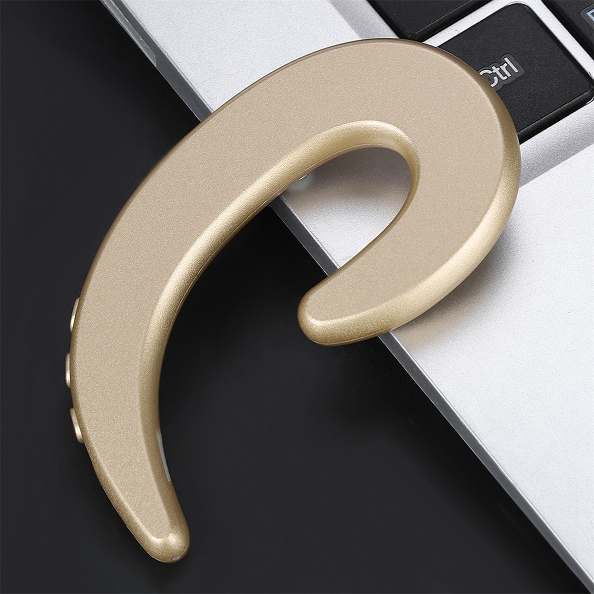 Goldfarbener Kopfhörer auf dem Laptop. Der Kopfhörer befindet sich in der Nähe der Tastatur.