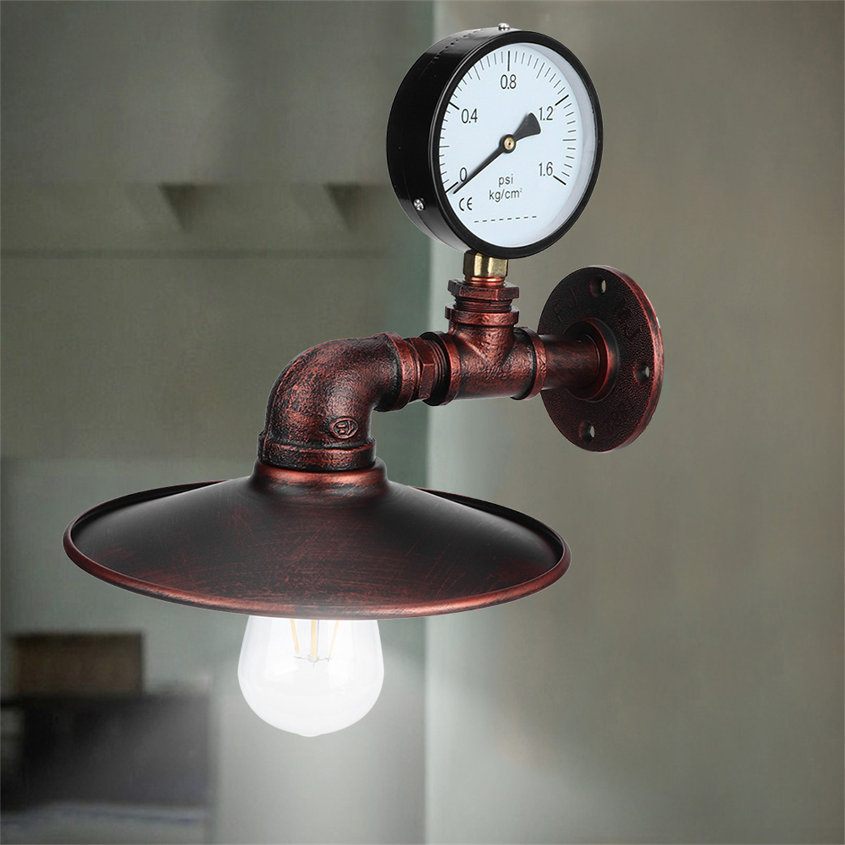 Eine Wandleuchte im Industriestil mit Messgerät, Kupferrohren und Lampenschirm. Die Glühbirne ist sichtbar.