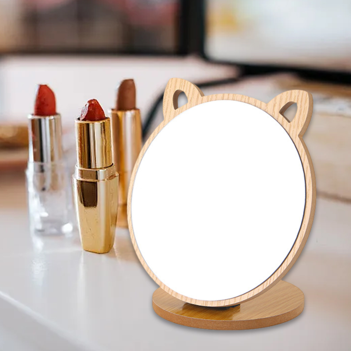 Holz-Katzenohrspiegel mit Lippenstift auf dem Tisch. Weißer, verschwommener Hintergrund.