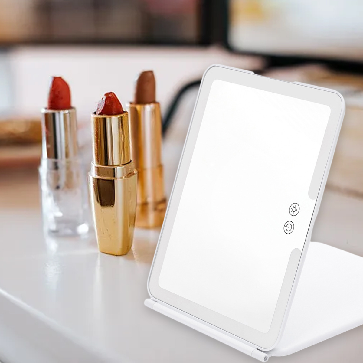 Weißer, beleuchteter Schminkspiegel mit Lippenstiften im Hintergrund. Knöpfe an der Seite.