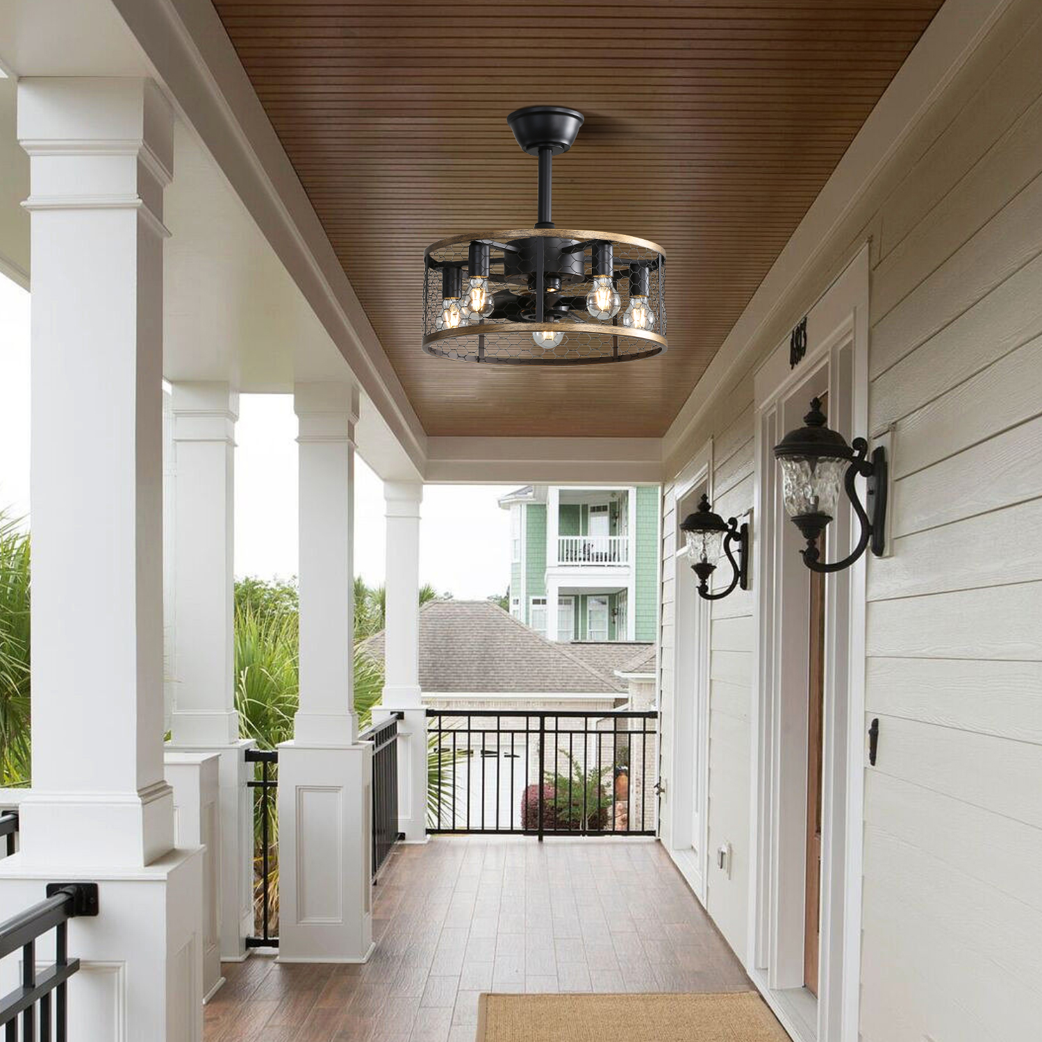 Außenveranda mit Deckenventilator, weißem Geländer und dekorativen Wandlampen.