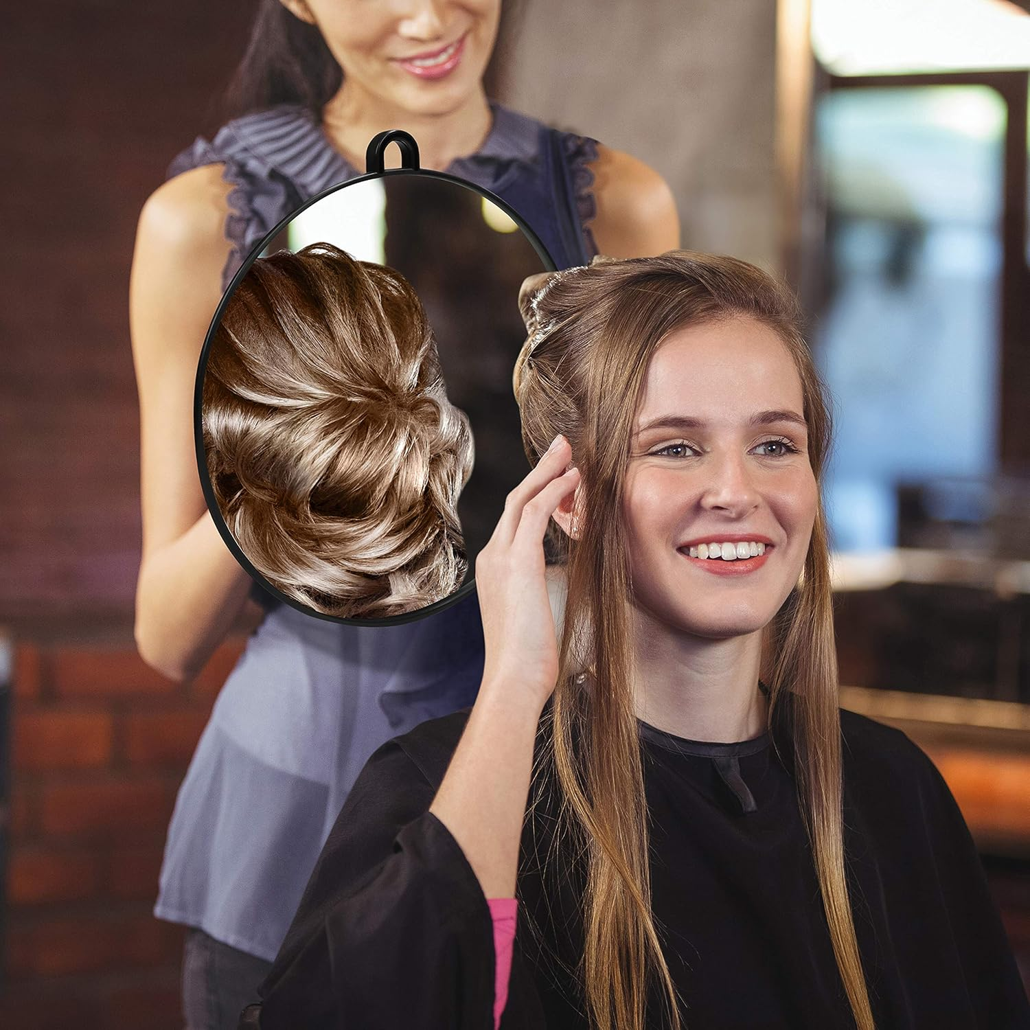 Das Haar einer Frau wird in einem Salon gestylt. Ein Spiegel zeigt die Rückseite des fertigen Stils. Die Frau lächelt.