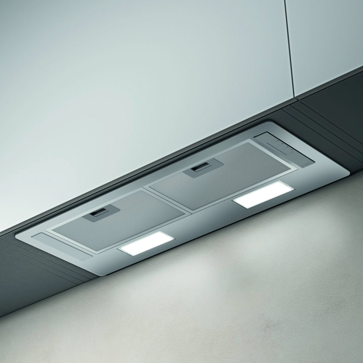 Cappa in acciaio inox con luci installata sotto un mobile bianco, sopra una parete chiara.