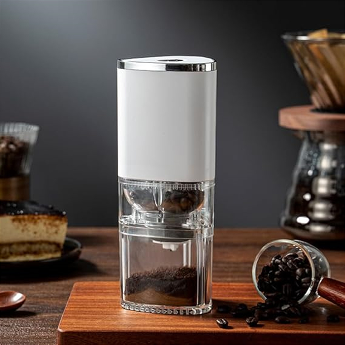 Elektrische Kaffeemühle in Weiß und Silber mit Kaffeebohnen und Kuchen.