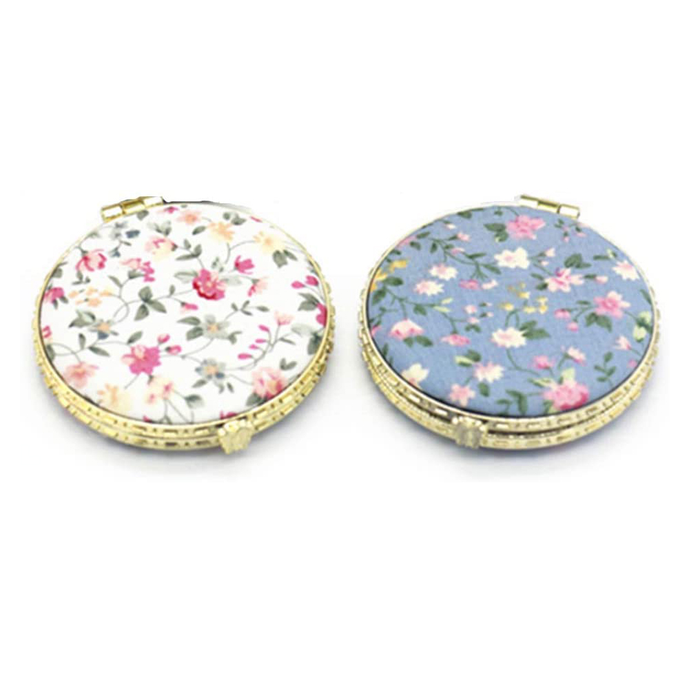 Zwei Kompaktspiegel mit floralen Stoffbezügen, einer weiß floral, einer blau floral.