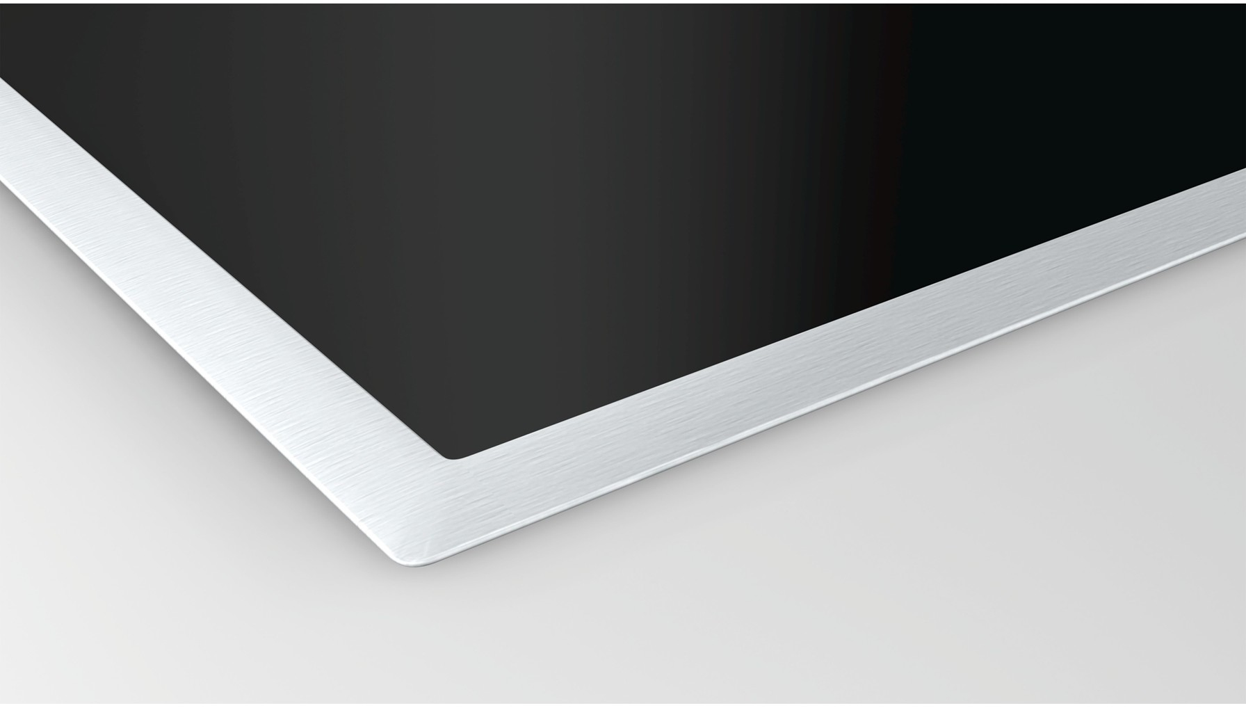 Elegancka, czarna, prostokątna płyta indukcyjna z krawędzią ze szczotkowanego metalu, widziana pod kątem.