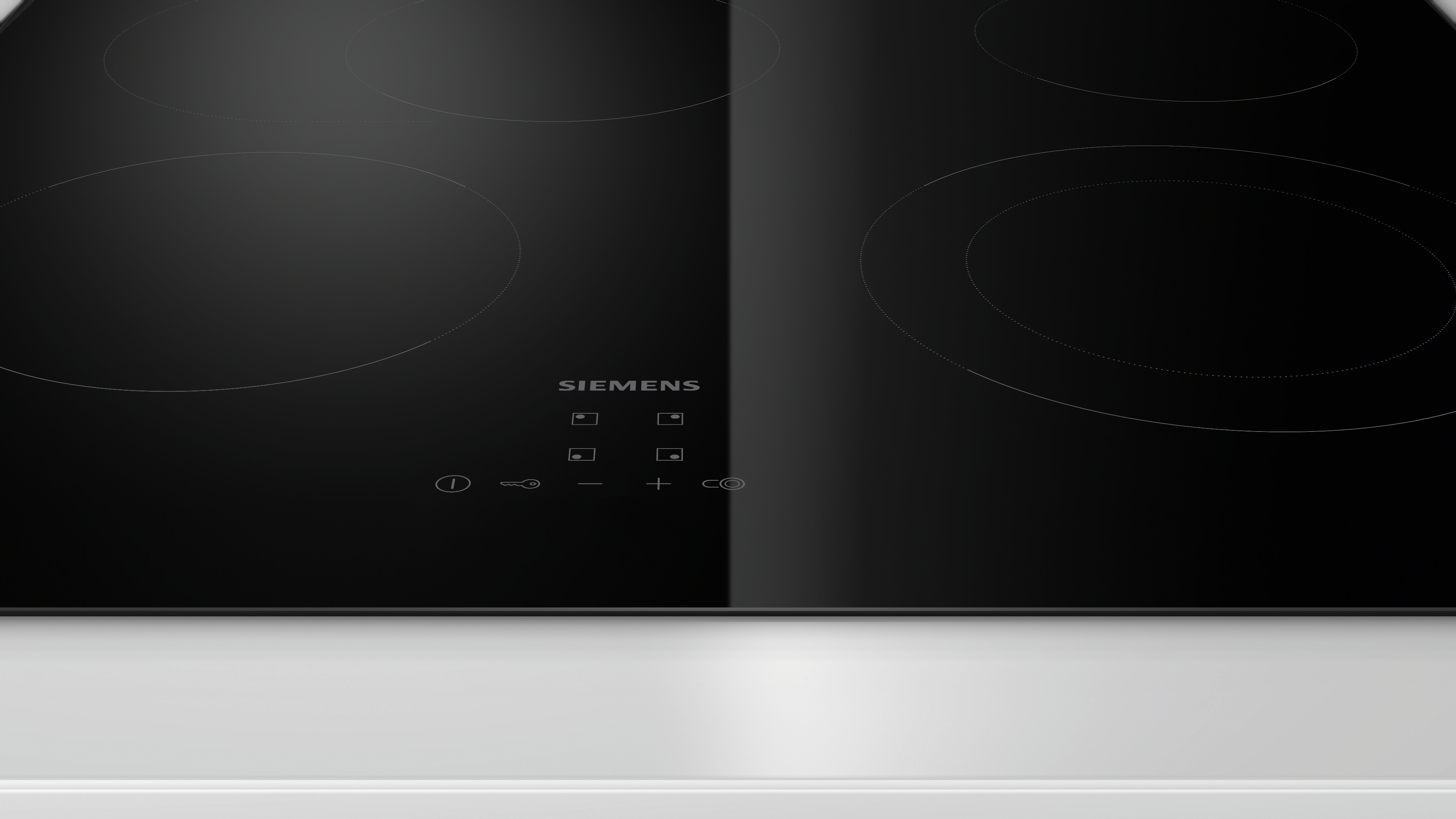Black induction cooktop with four cooking zones and touch controls. 
