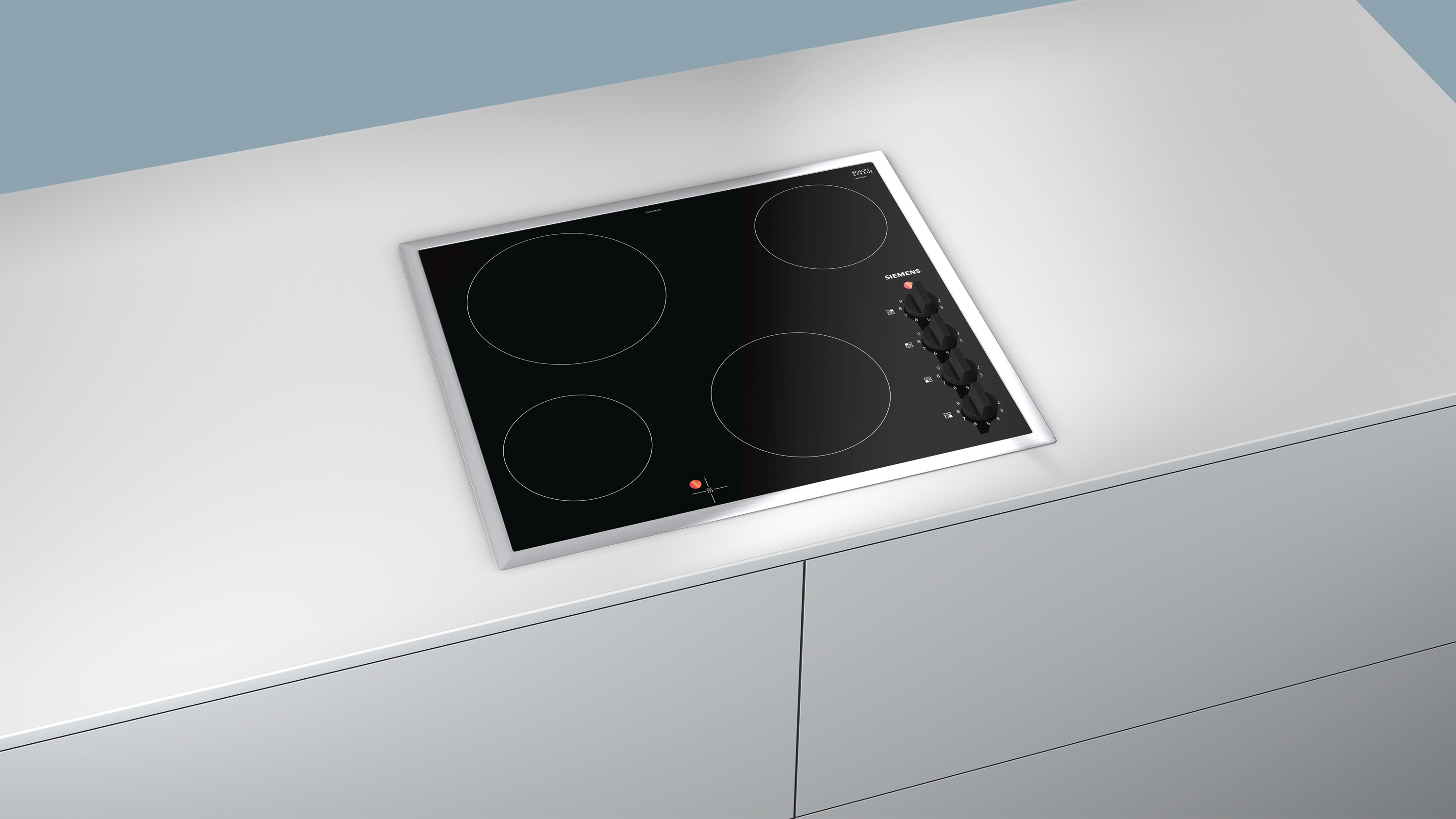 Table de cuisson à induction noire avec quatre brûleurs. Marque Siemens sur un plan de travail blanc.