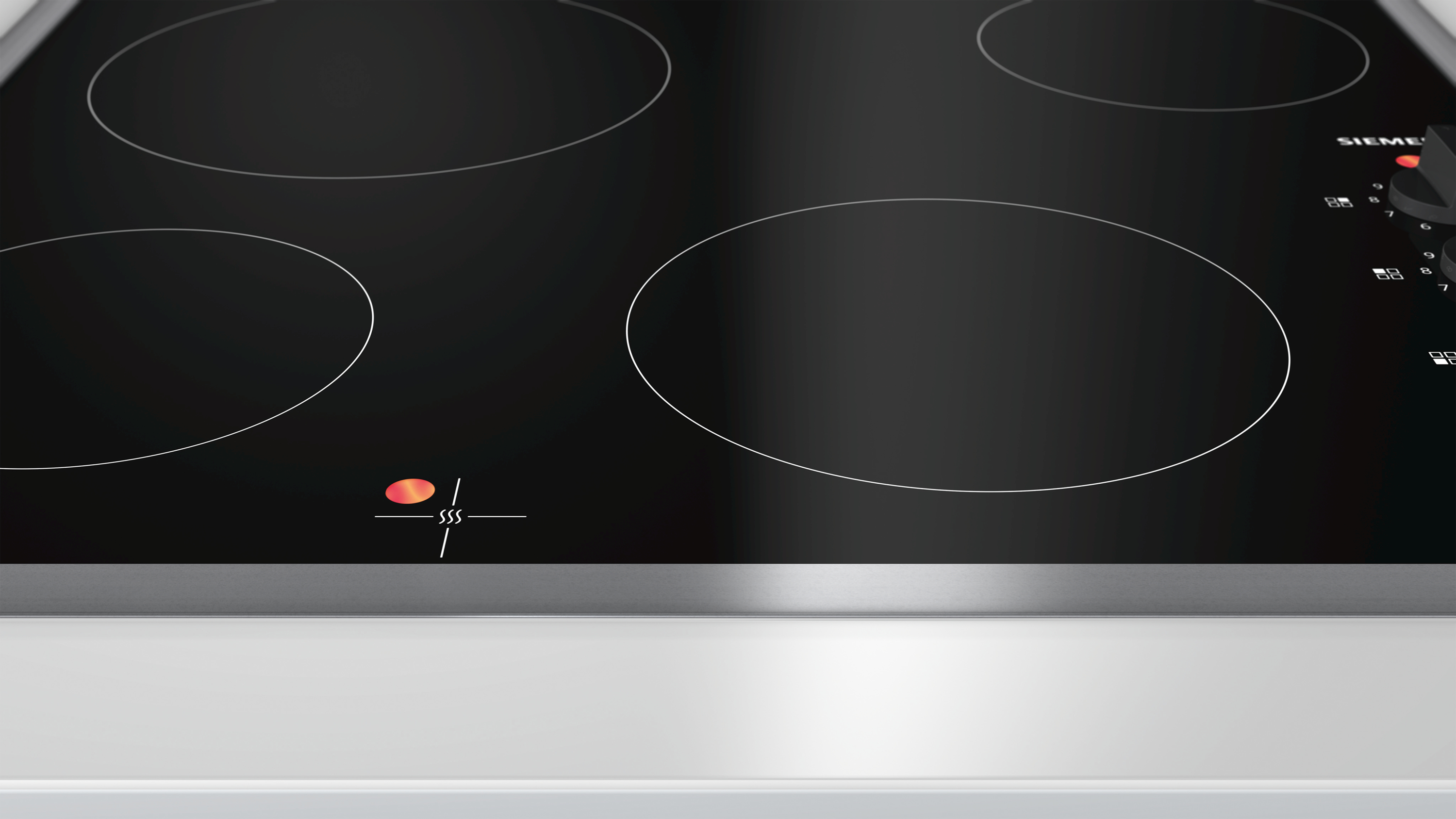 Table de cuisson à induction noire avec quatre zones de cuisson circulaires.