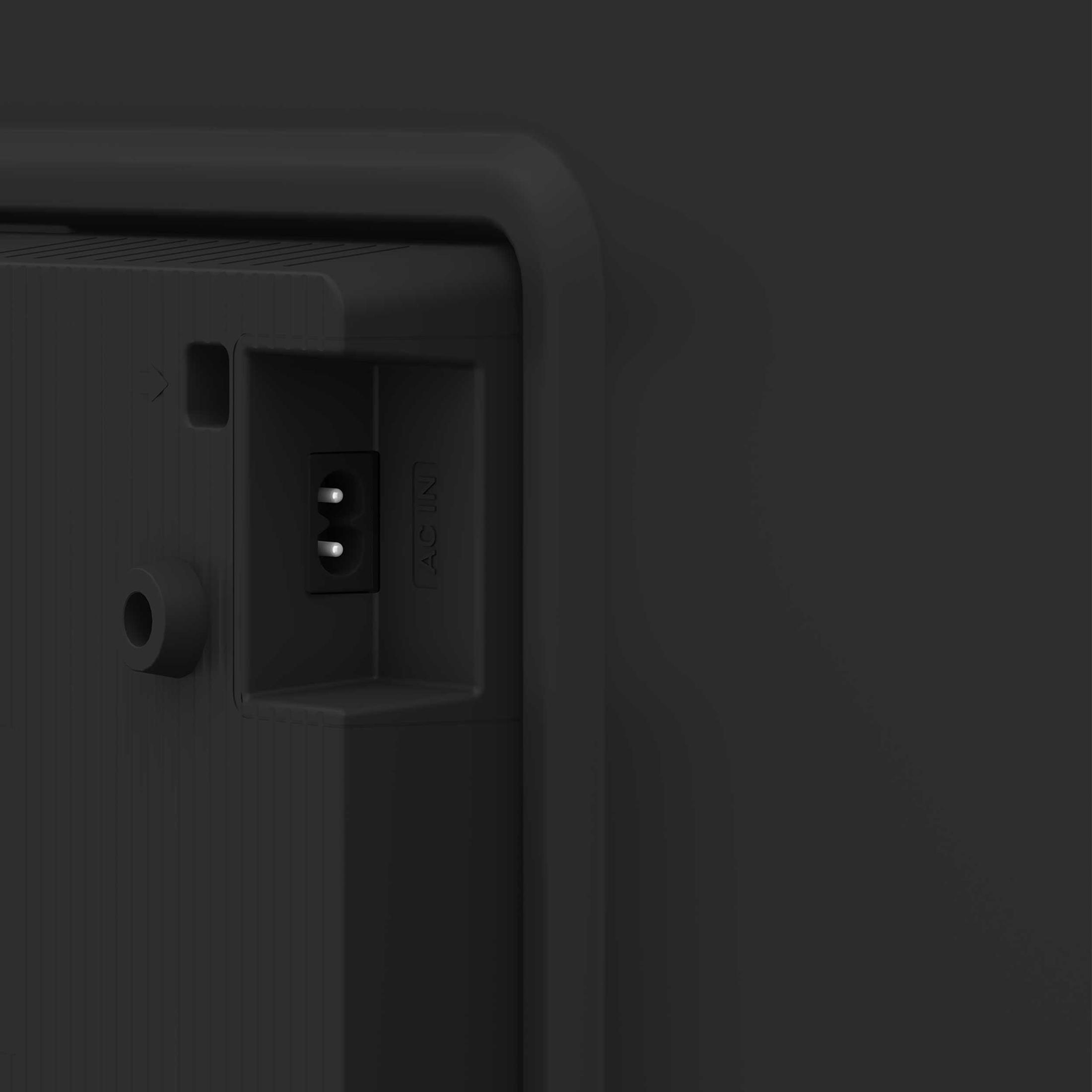 Zbliżenie tyłu czarnego telewizora. Pokazuje port zasilania AC IN.