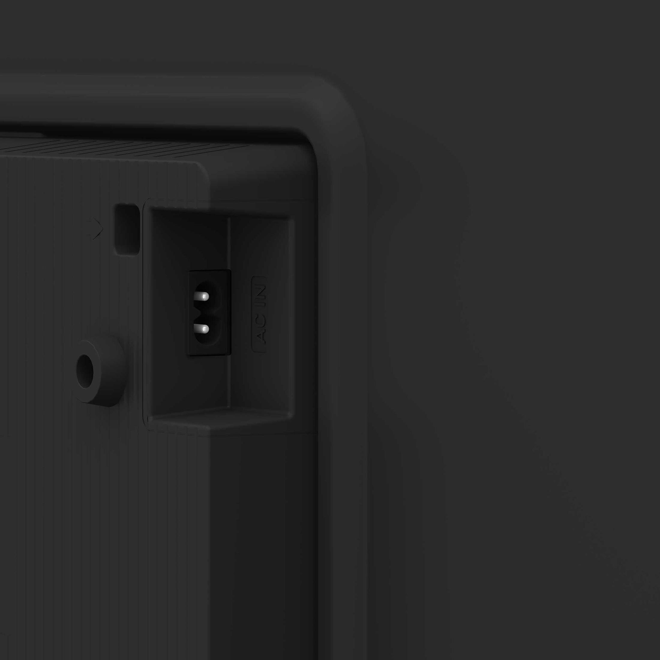 Zbliżenie obszaru wejścia zasilania telewizora z czarnym tłem. Widoczny port AC IN z dwoma bolcami.