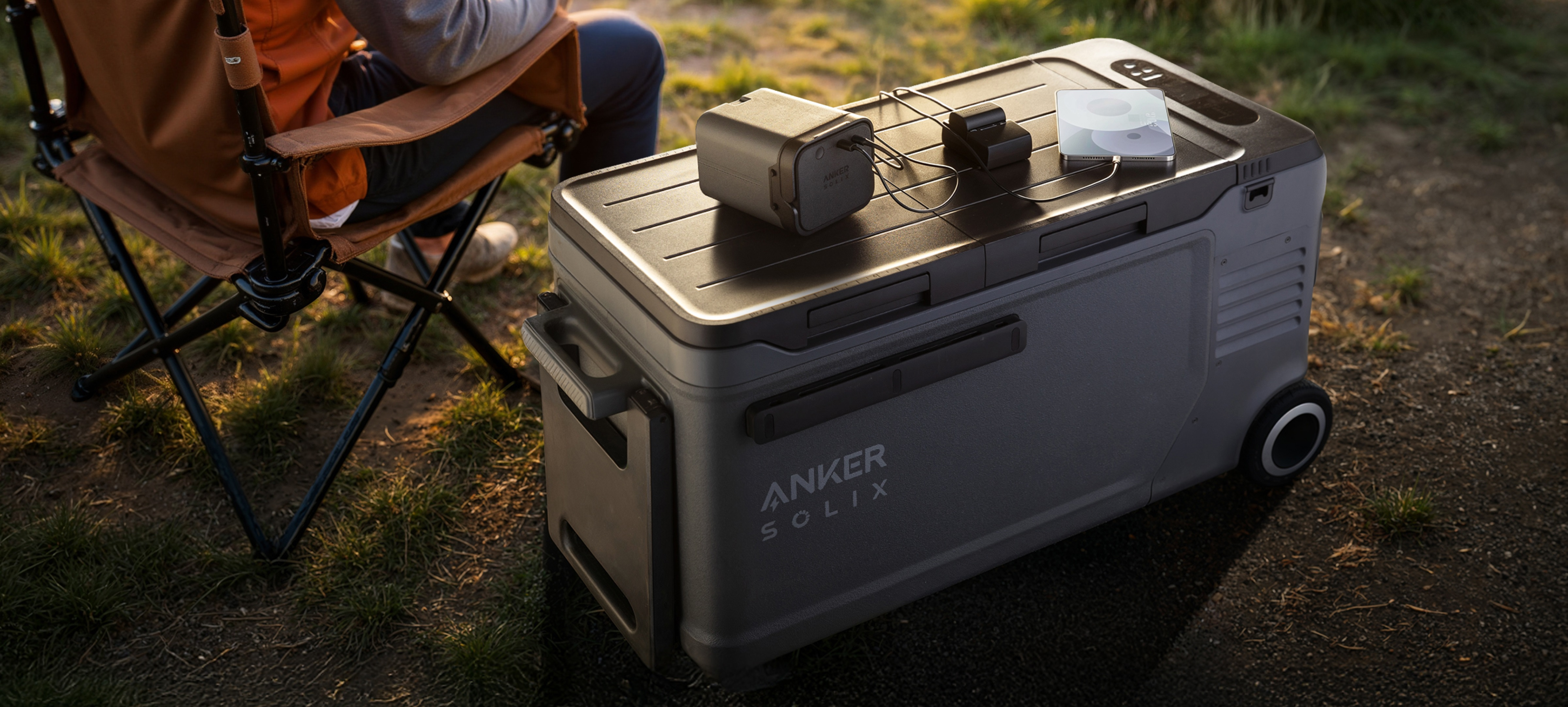 Lodówka z akcesoriami na górze, osoba siedząca na krześle w tle.