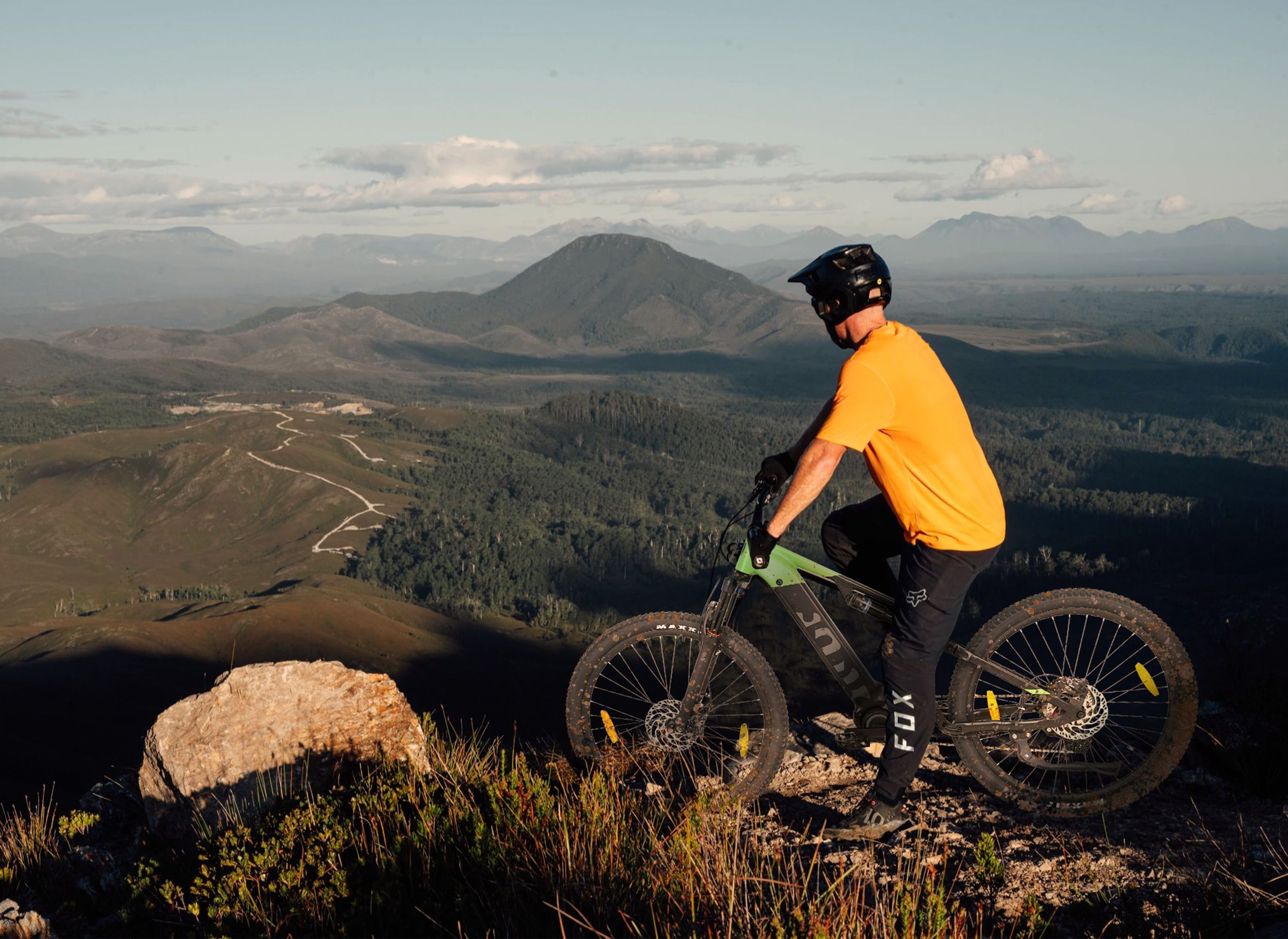 Ein Mann auf einem Mountainbike mit Blick auf eine malerische Landschaft. Der Himmel ist klar und der Tag sonnig.