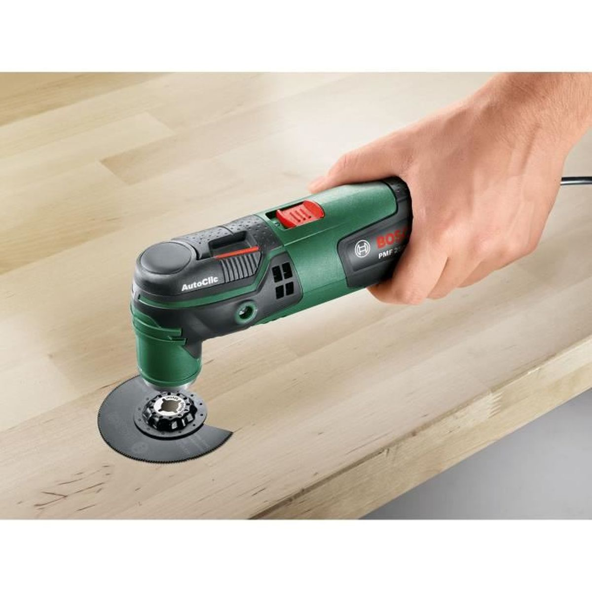 Una mano che tiene un multiutensile Bosch PMF 220 CE che taglia una superficie in legno.