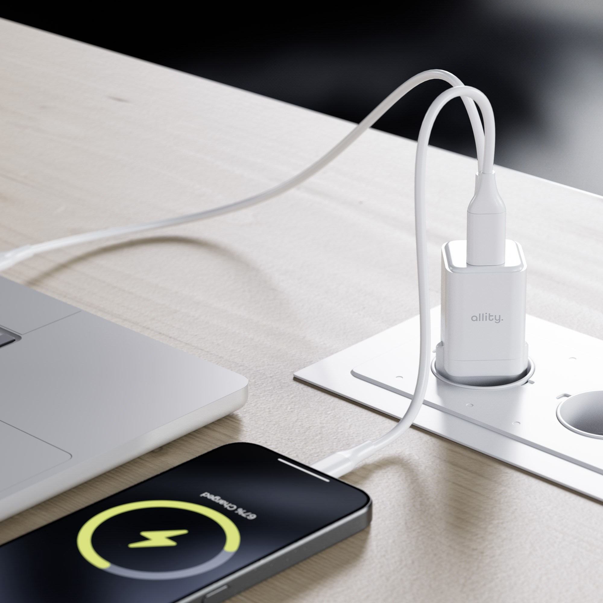 Telefon ładujący się na drewnianym stole, biała ładowarka wpięta do białego gniazdka.