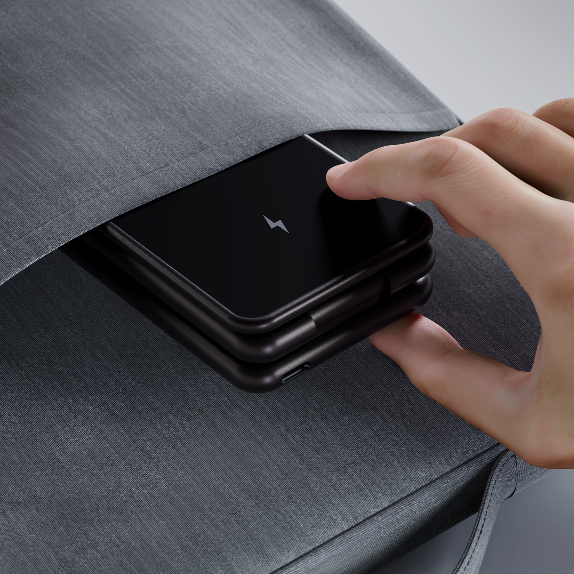 Ręka wkładająca czarny telefon z błyskawicą do szarej kieszeni.