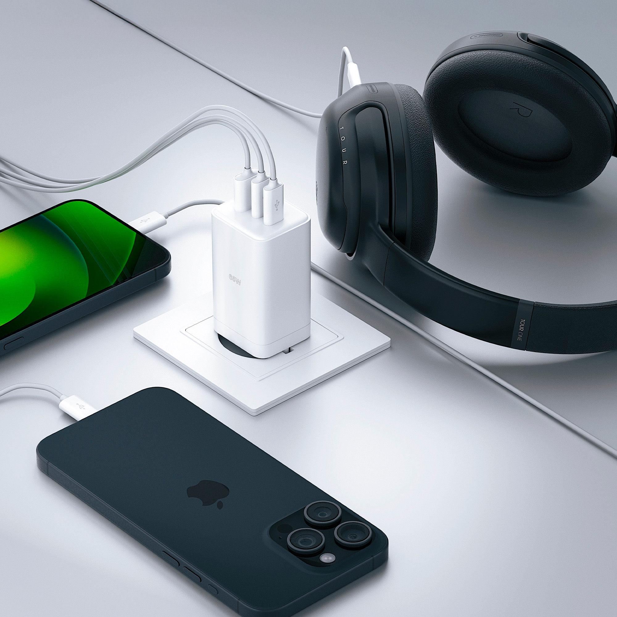 Biały adapter ładowania z 3 portami USB podłączony do gniazdka, z telefonami i słuchawkami.