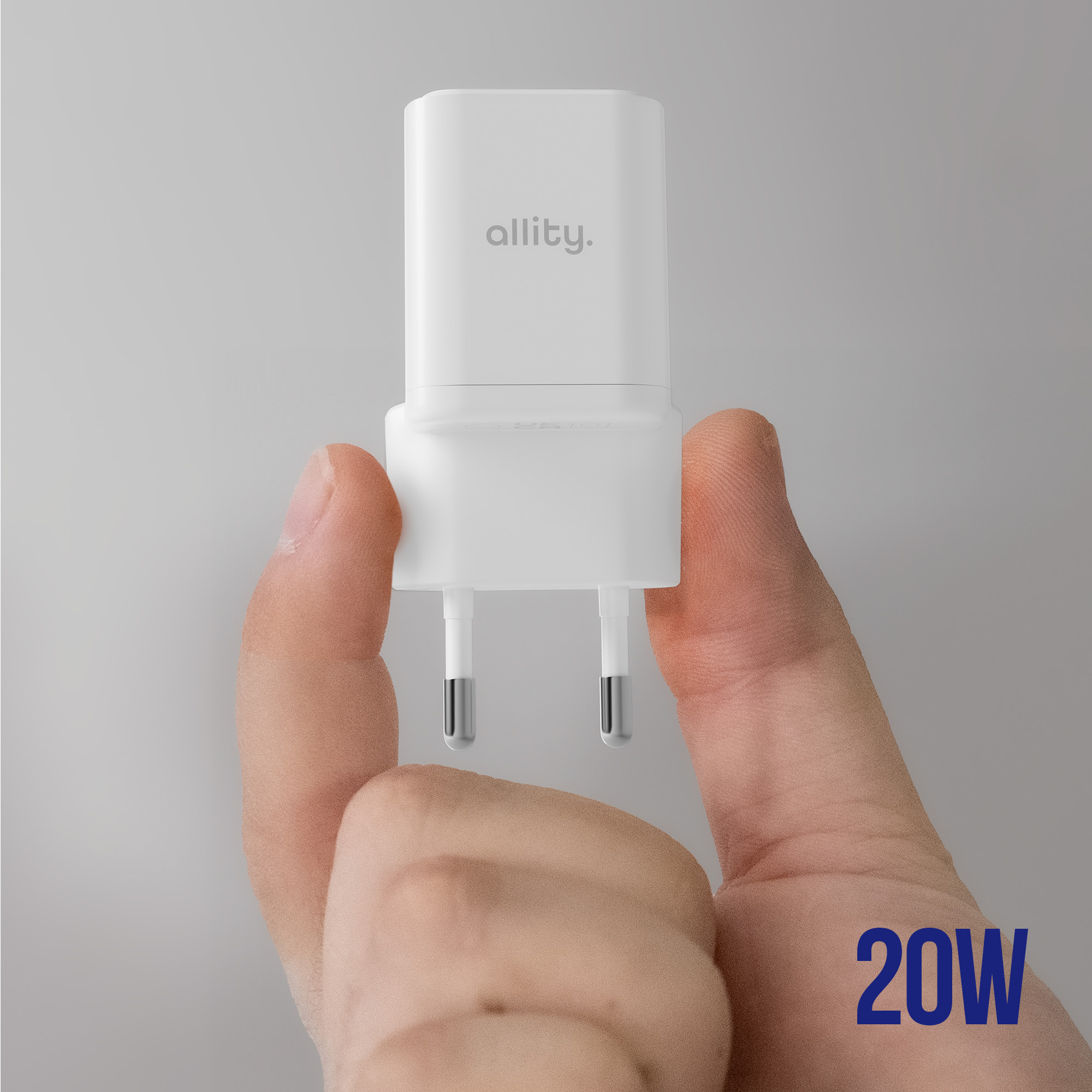 Biała ładowarka z pinami, trzymana przez dłoń, logo allity.. Tekst 20W, szare tło.