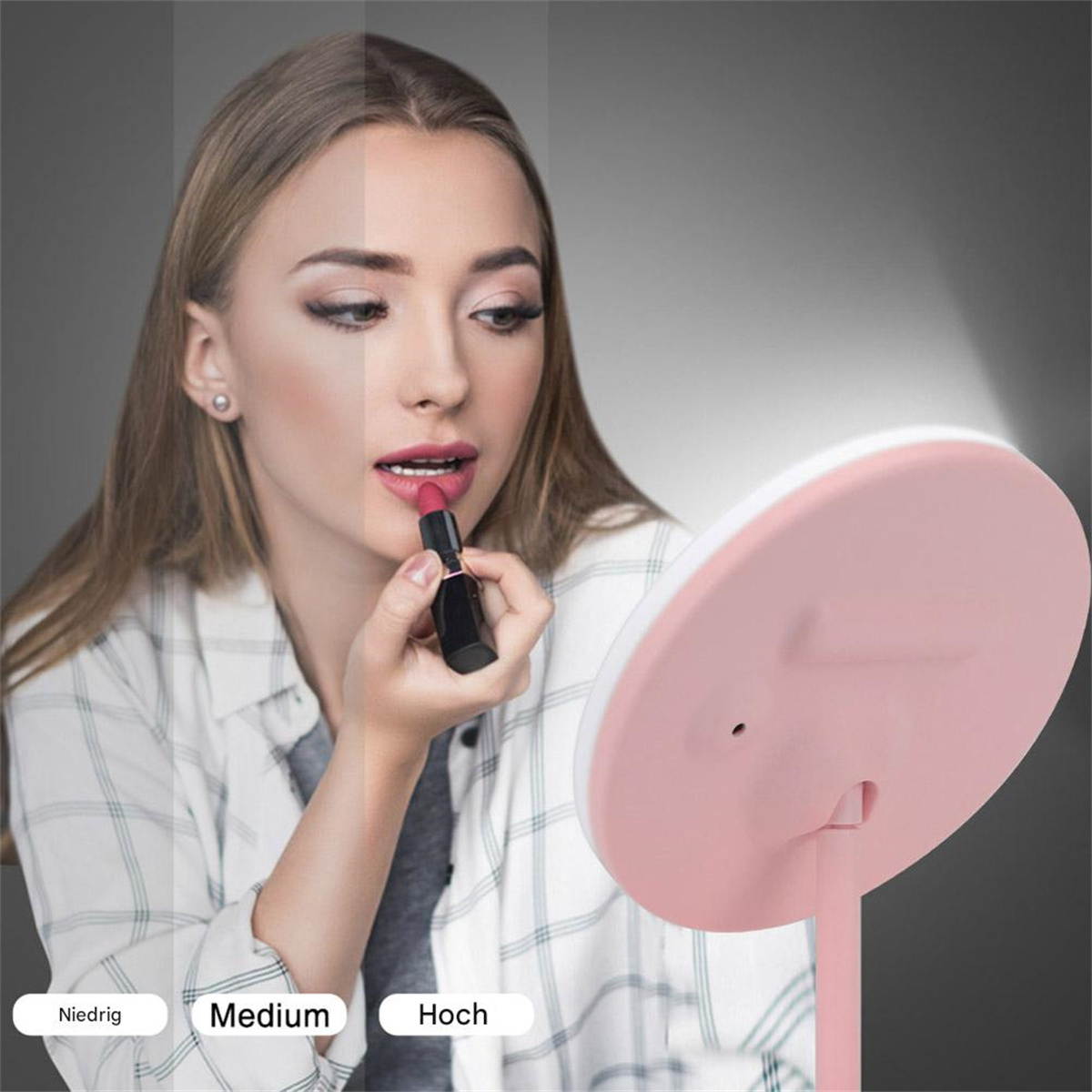 Frau, die Lippenstift mit einem rosa Spiegel aufträgt, mit Beleuchtungsoptionen: Niedrig, Medium und Hoch.