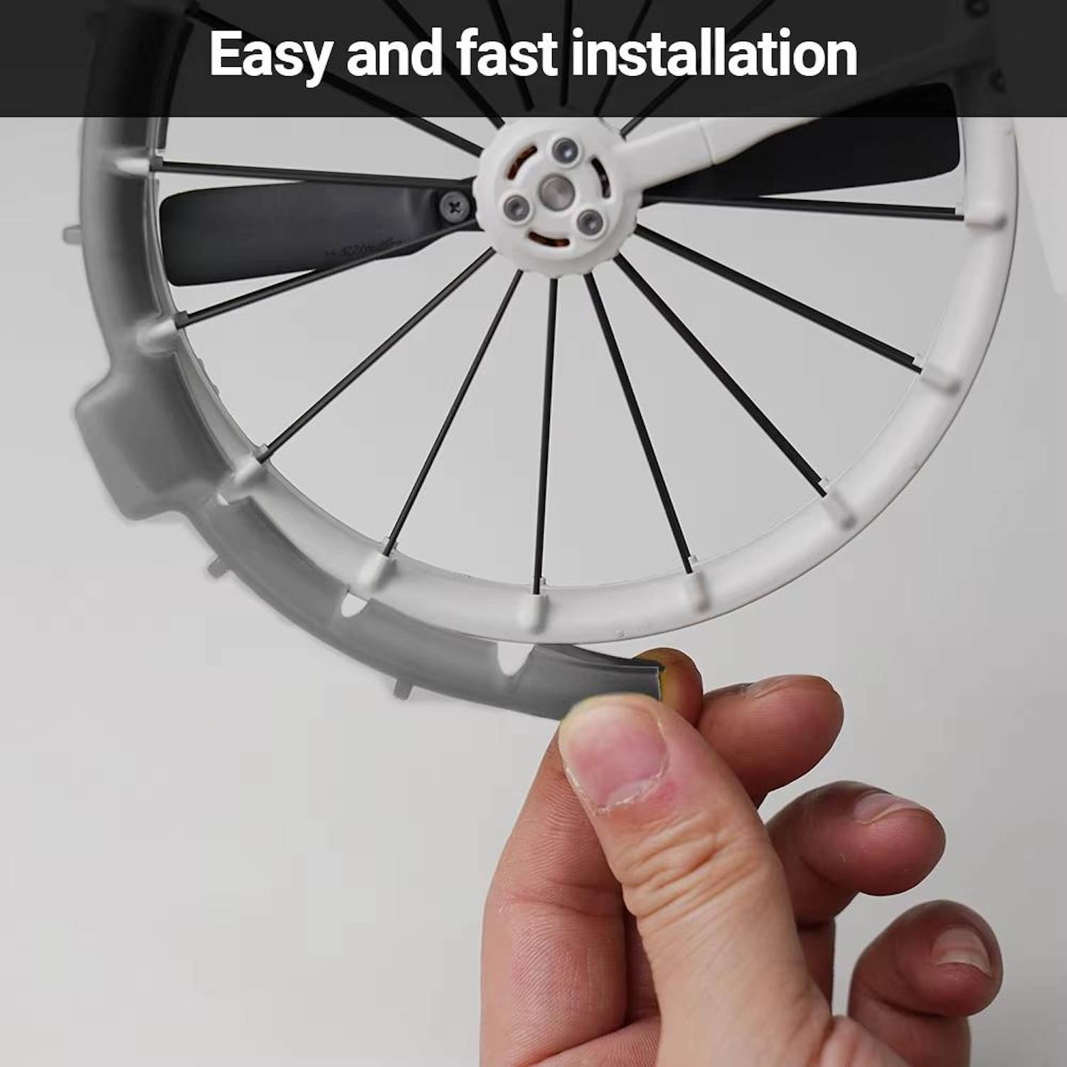 Eine Hand hält ein graues Stück des Propellerschutzes einer Drohne in der Nähe der Drohne.
