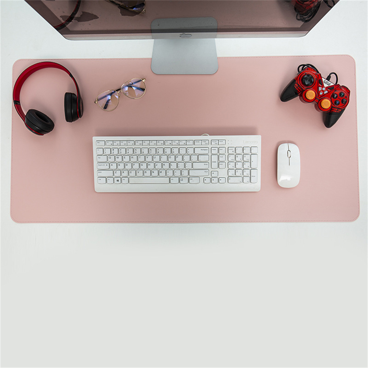 Ein rosa Schreibtischpad mit Tastatur, Maus, Kopfhörern, Brille und Gamecontroller.