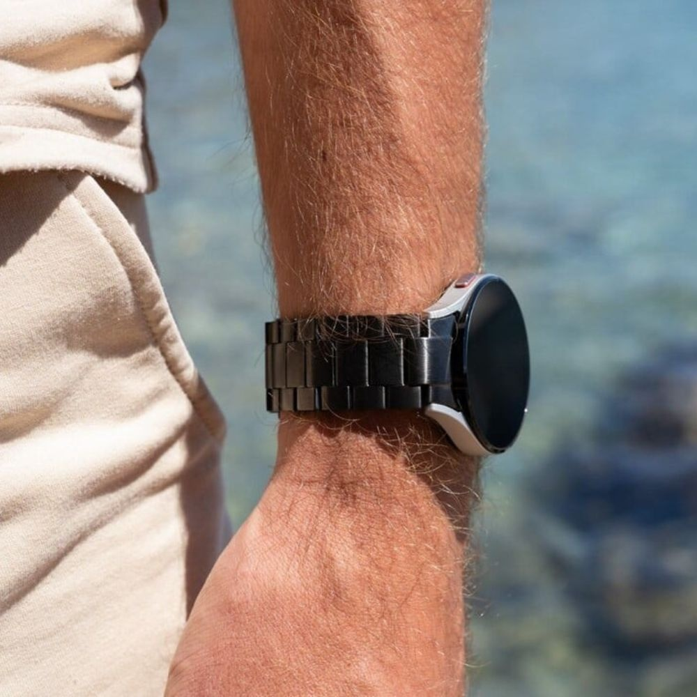 Mann mit schwarzer Uhr mit Metallband. Wasser Hintergrund.