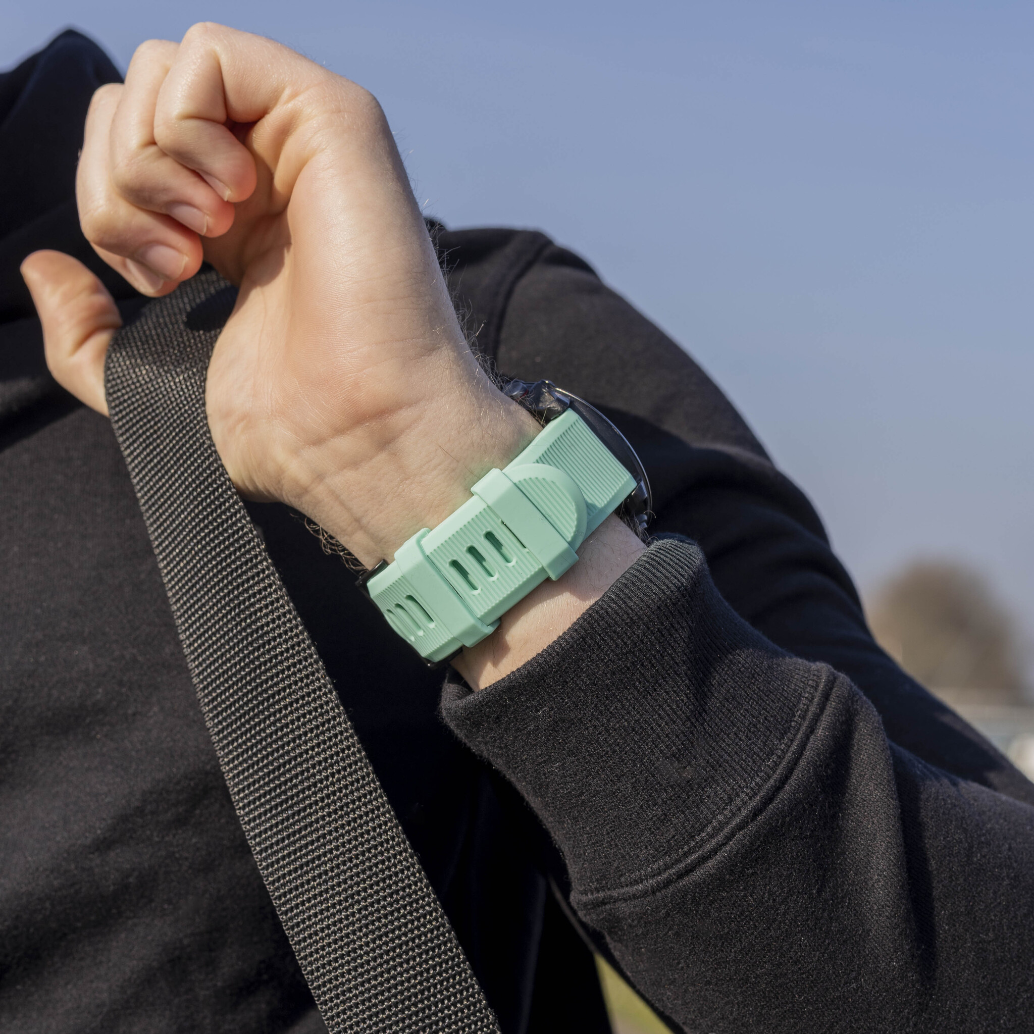 Das Handgelenk einer Person mit einem grünen Uhrenarmband. Die Uhr wird getragen.