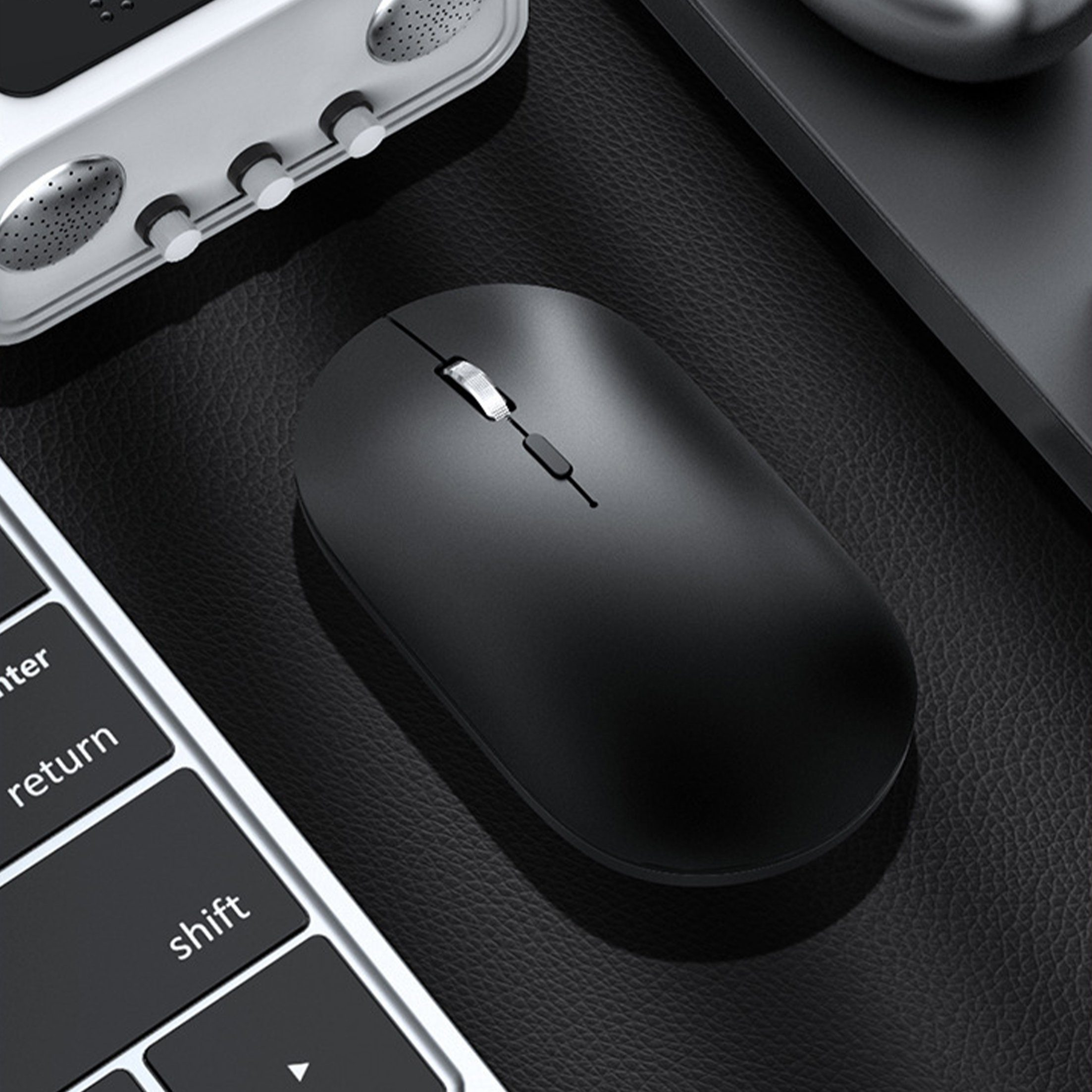Schwarze kabellose Maus auf schwarzer Oberfläche mit Tastatur. Weißer Hintergrund.