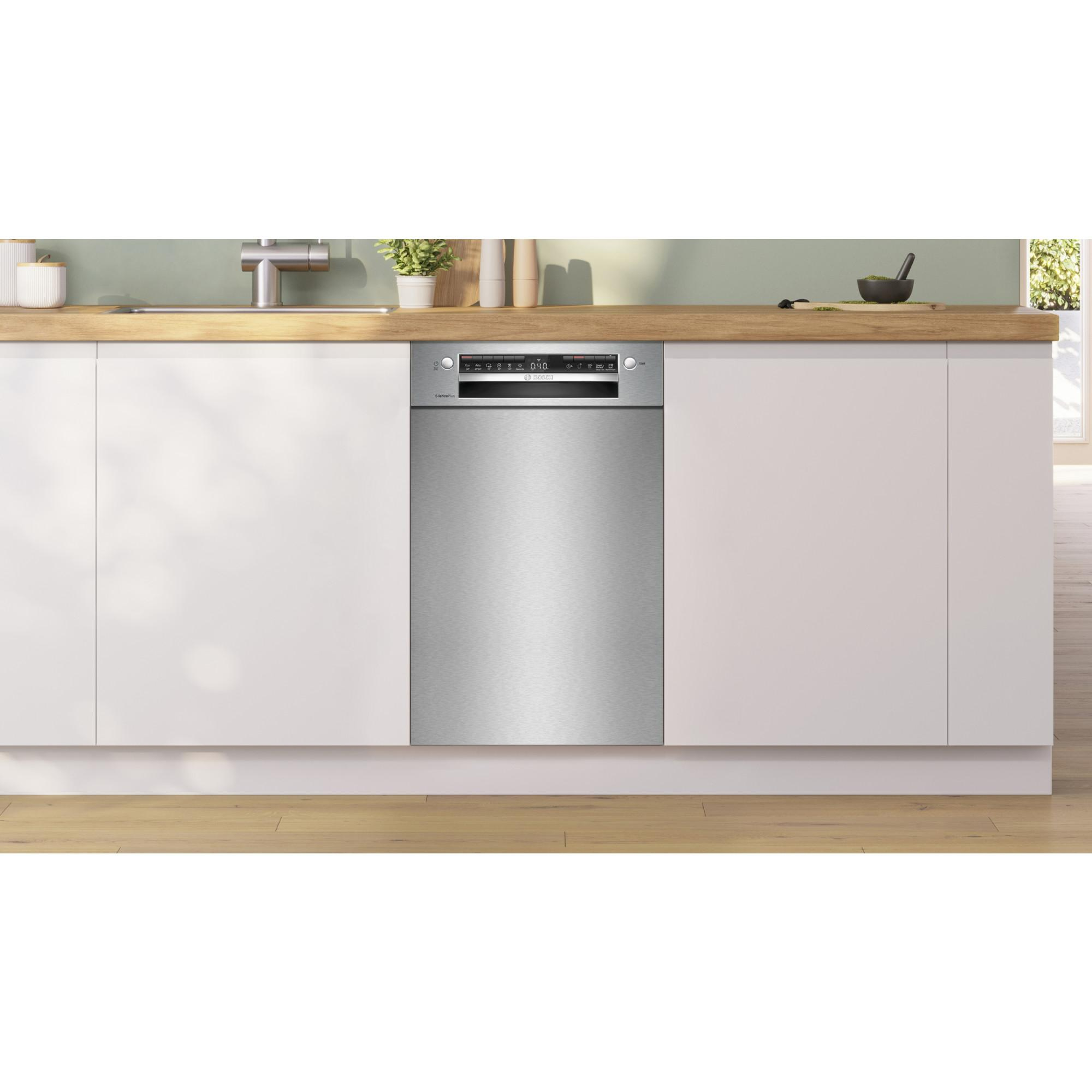 Lavastoviglie in acciaio inox in un ambiente cucina, tra mobili bianchi e piano di lavoro in legno.
