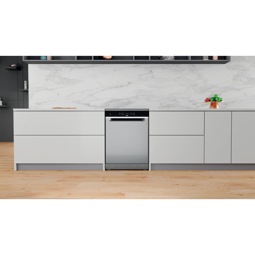 Cucina con lavastoviglie in acciaio inox e mobili bianchi. Pavimento in legno. Alzatina in marmo.