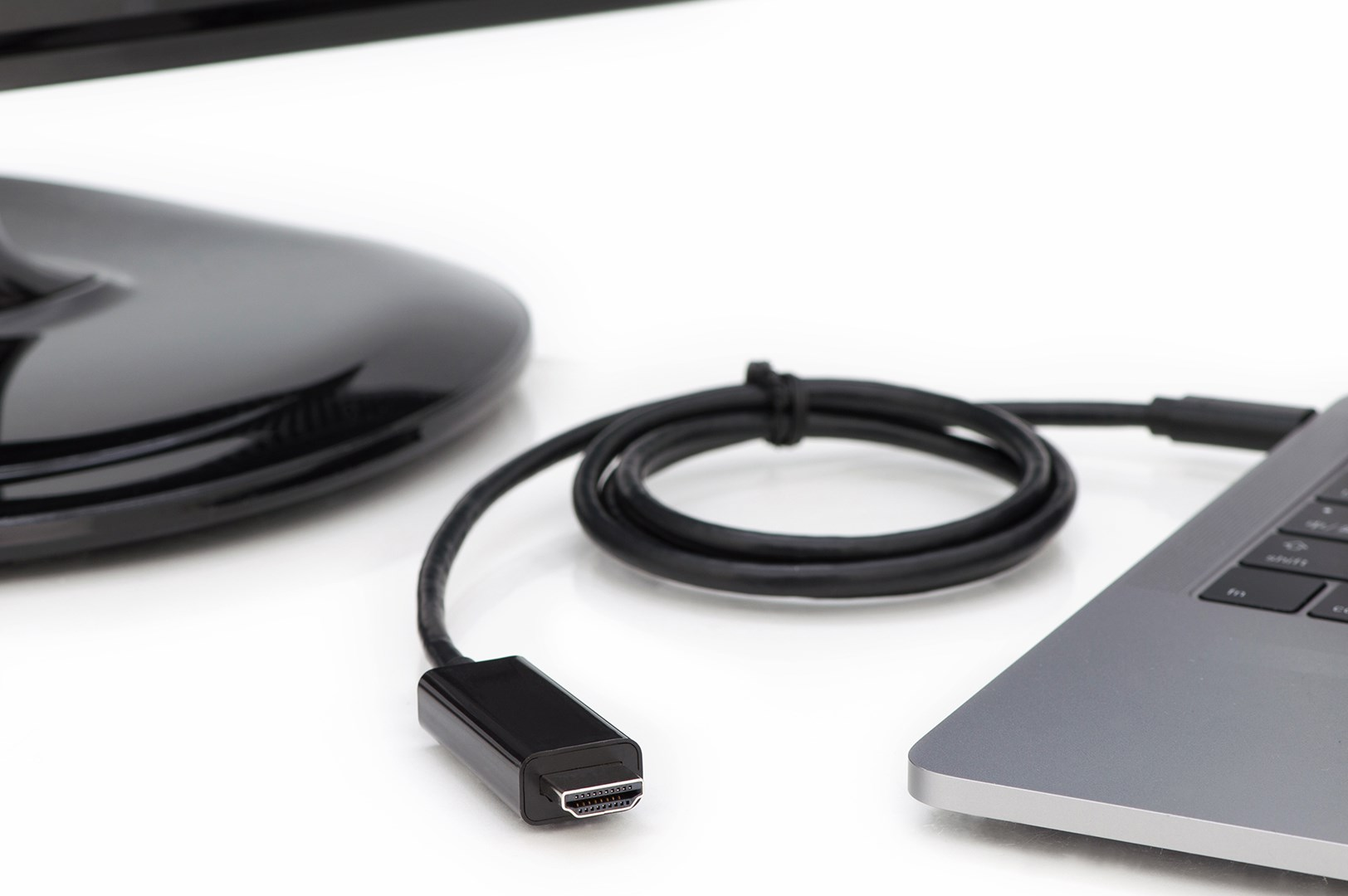Ein HDMI-Kabel, das mit einem Laptop und einem Monitor verbunden ist, auf weißem Hintergrund.