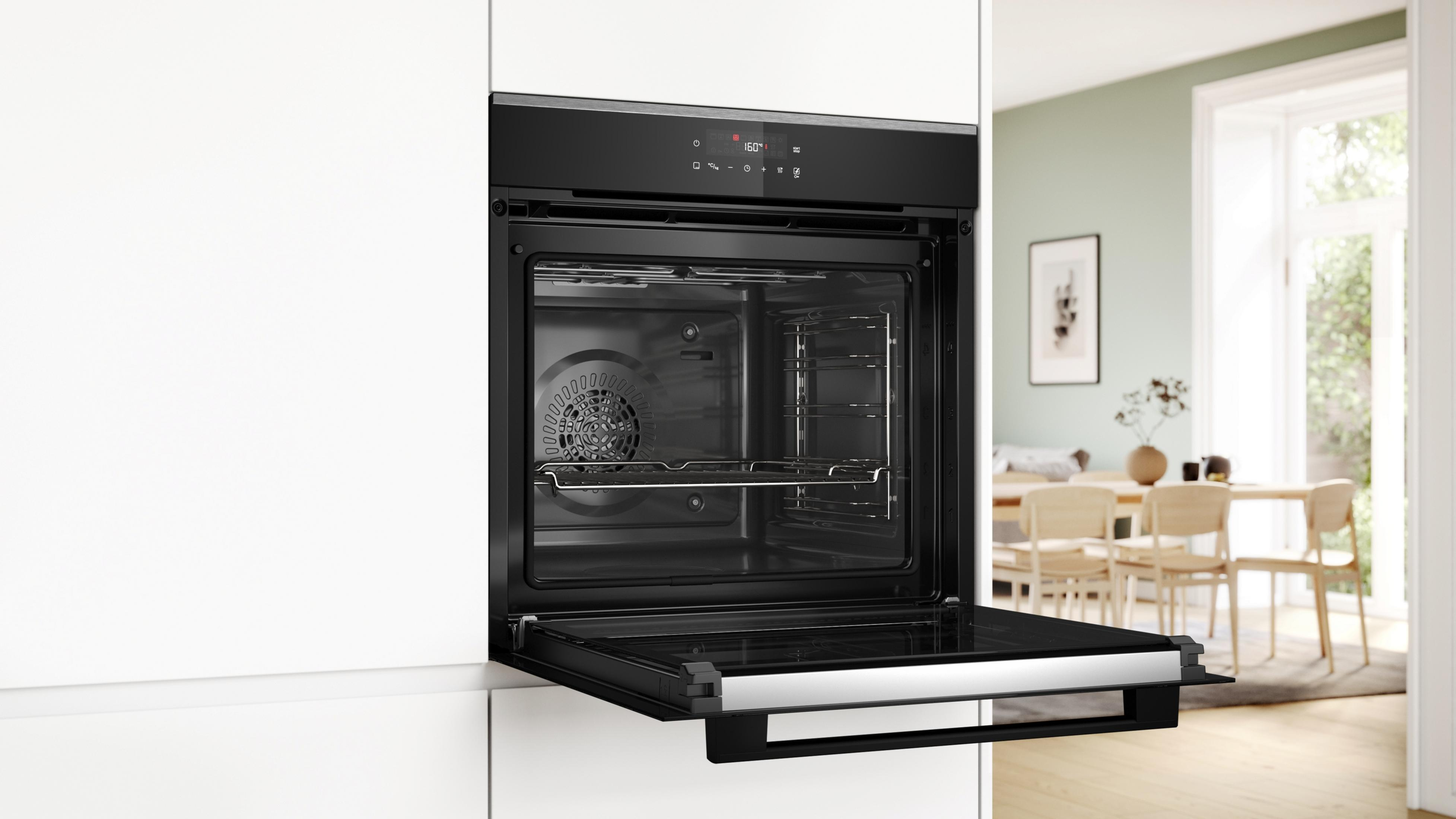 Un forno a incasso con la porta aperta, che mostra le caratteristiche interne e la cucina circostante.