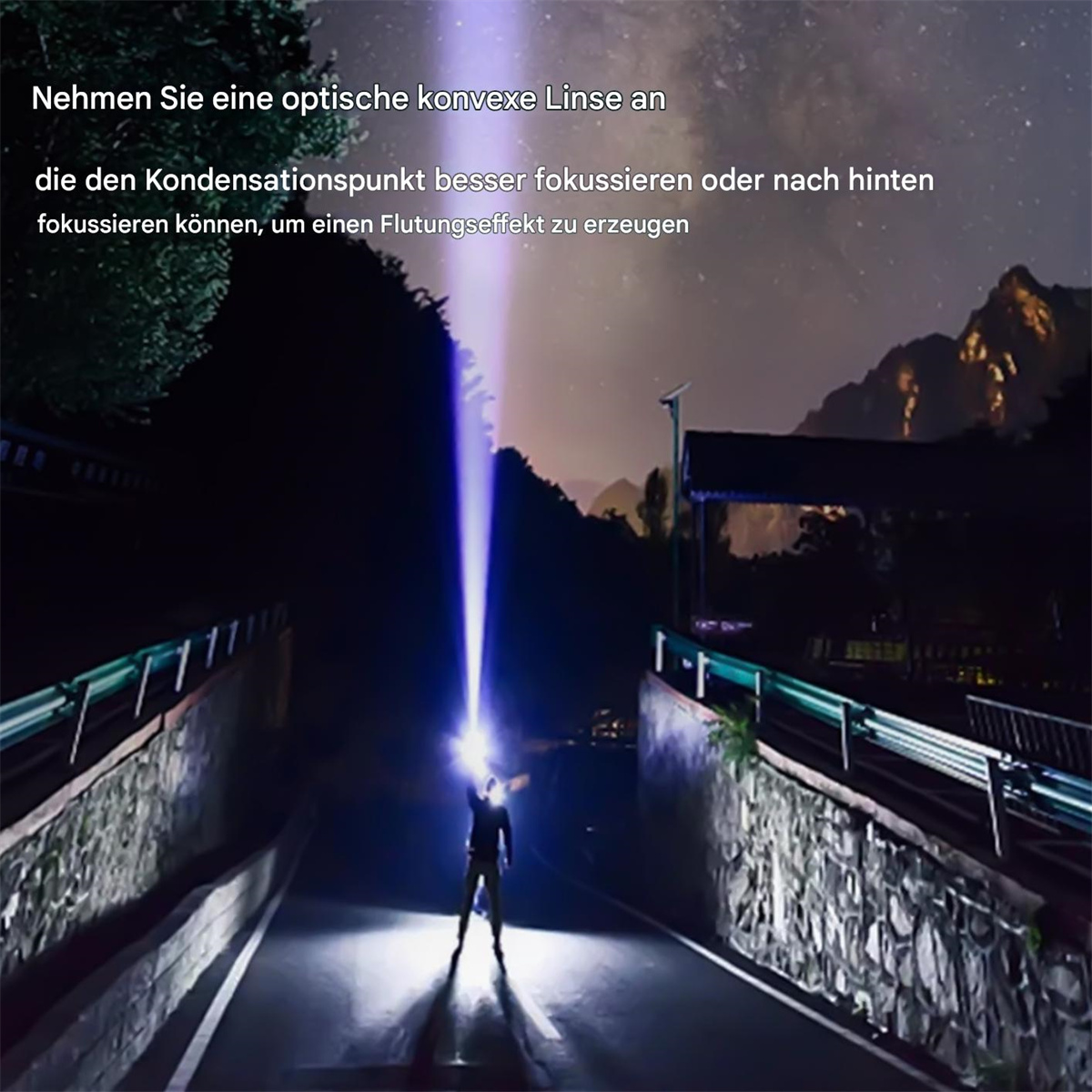 Person hält eine Taschenlampe und erzeugt einen hellen Strahl nach oben. Eine Straße und Brücke sind im Vordergrund. Berge und Himmel im Hintergrund.