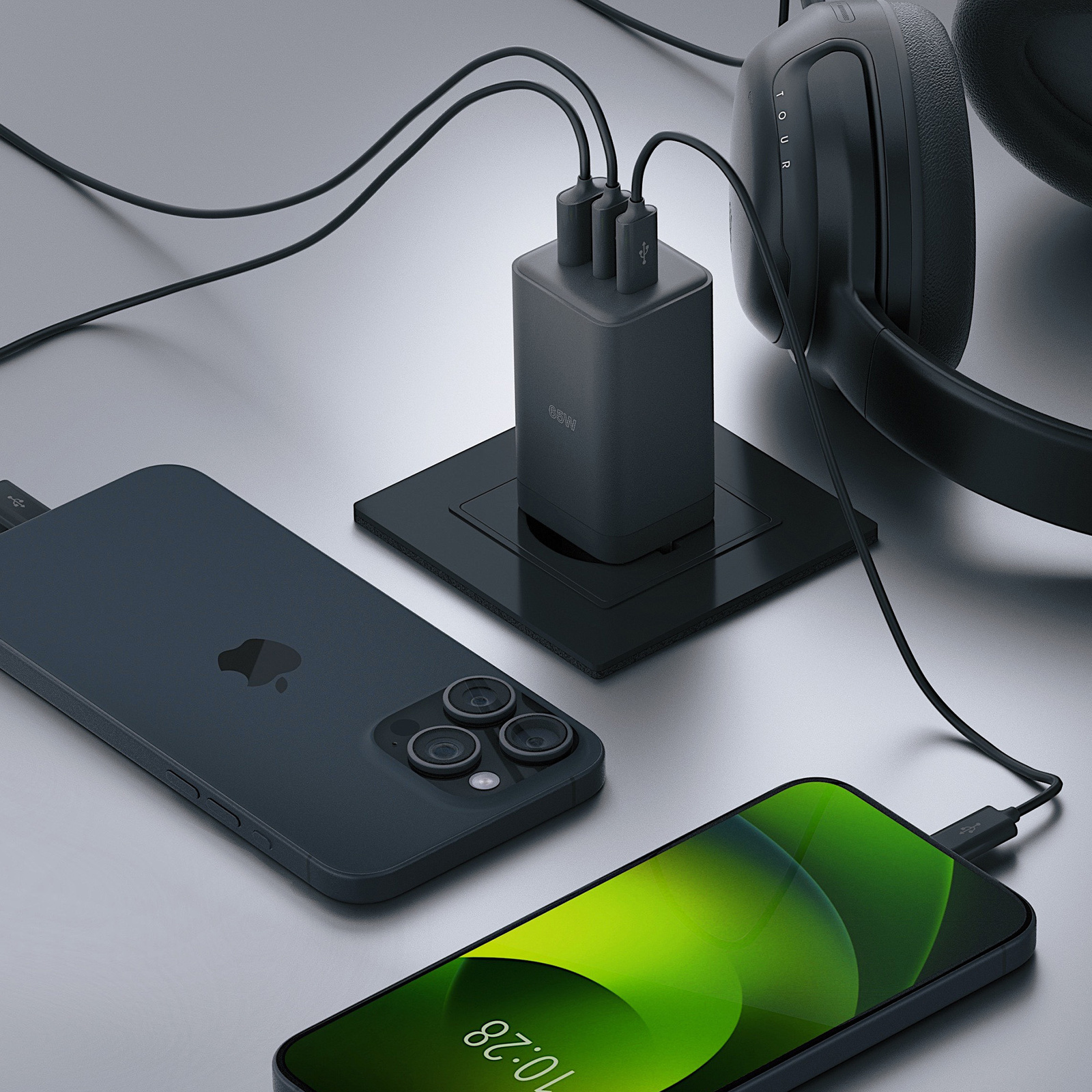 Telefon i słuchawki ładowane z ładowarki wieloportowej. Ciemny motyw kolorystyczny. Srebrna powierzchnia.