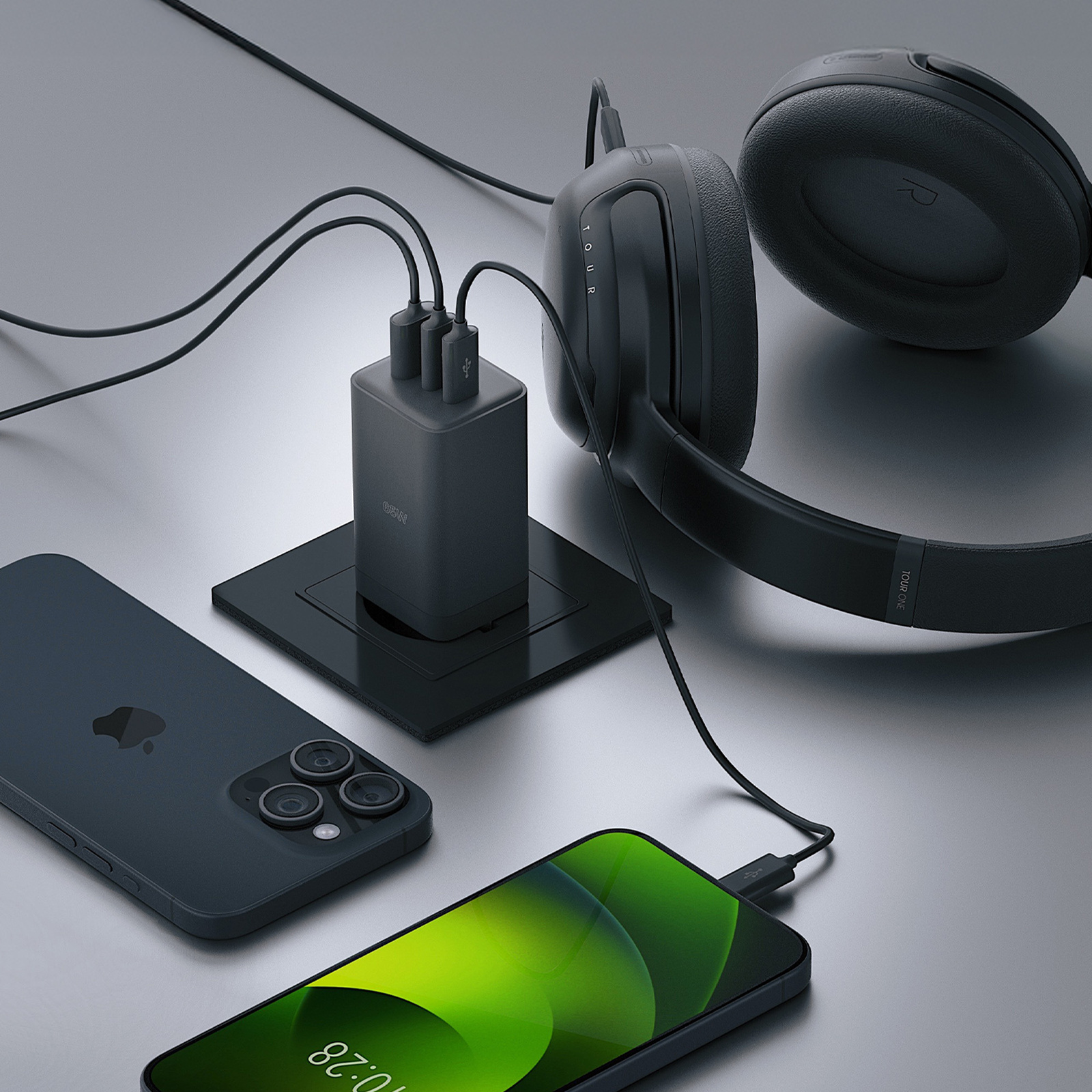 Czarna ładowarka z trzema portami podłączona do telefonu, słuchawek i gniazdka.