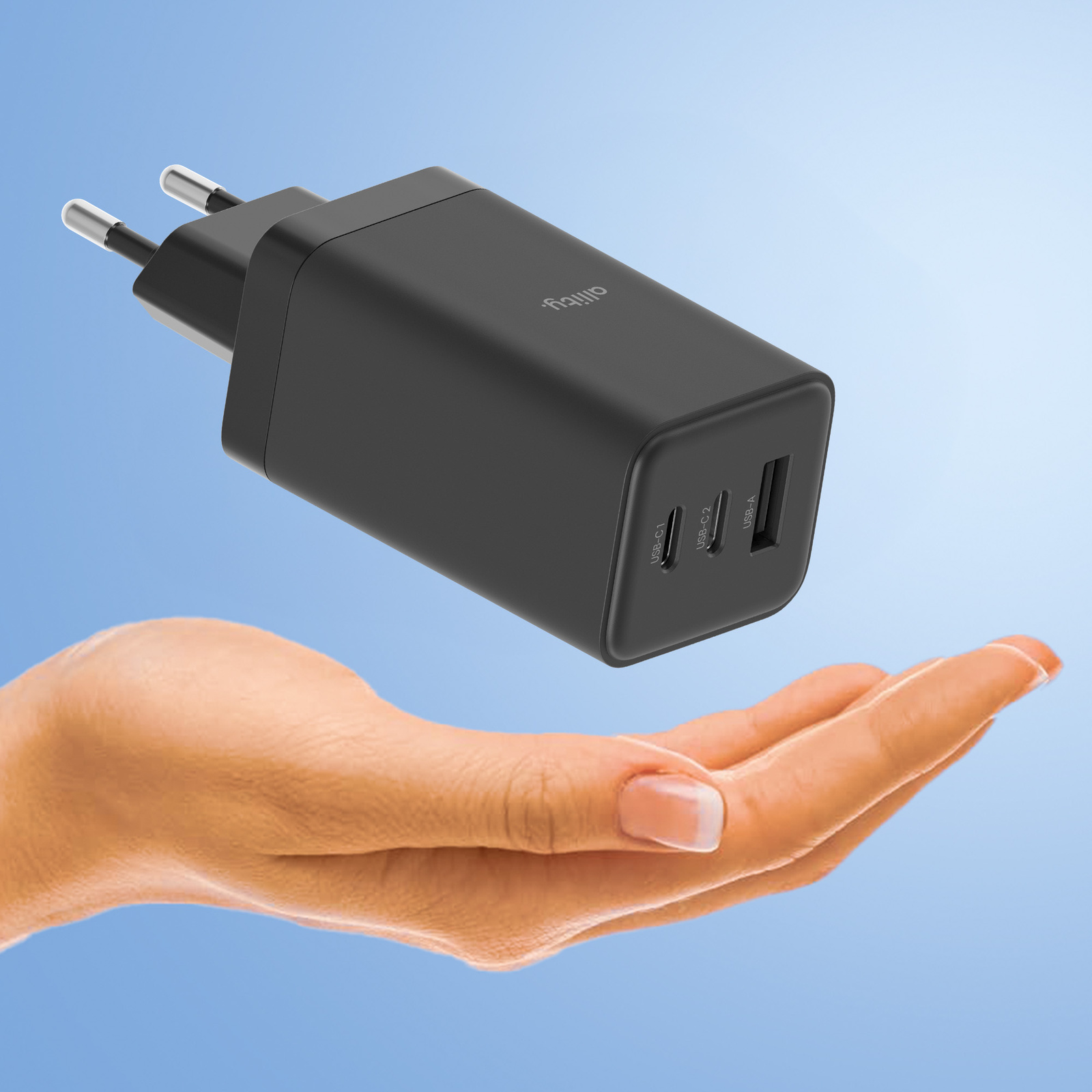 Czarna ładowarka trzymana przez dłoń na niebieskim tle z gradientem.