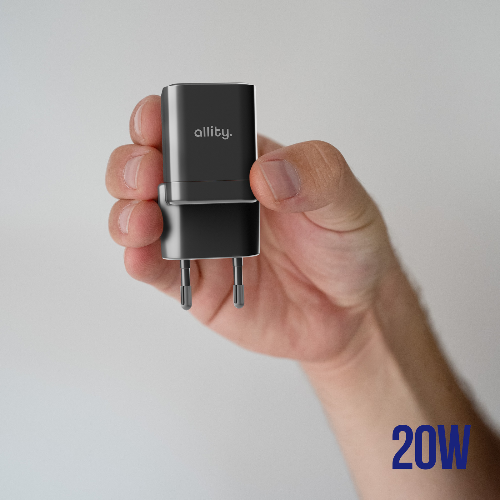 Ręka trzymająca czarną ładowarkę z napisem '20W' na dole.