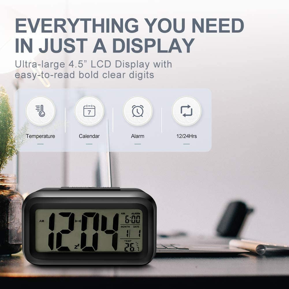 Schwarzer digitaler Wecker mit Display. Er zeigt Zeit, Datum und Temperatur an. Vier Symbole sind sichtbar.