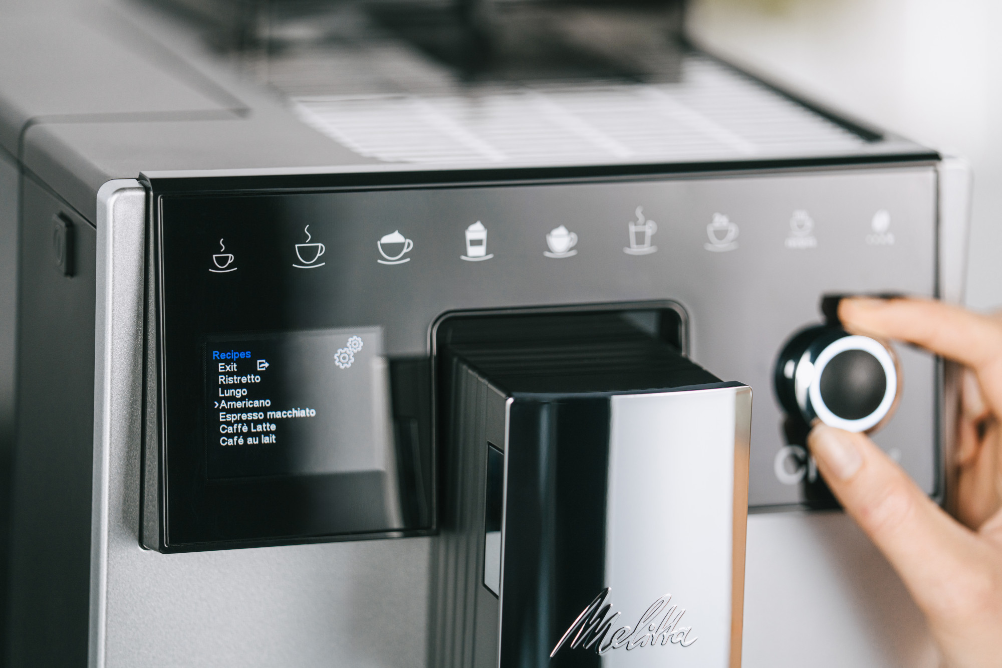 Ekspres do kawy z wyświetlaczem cyfrowym i dłonią regulującą pokrętło.