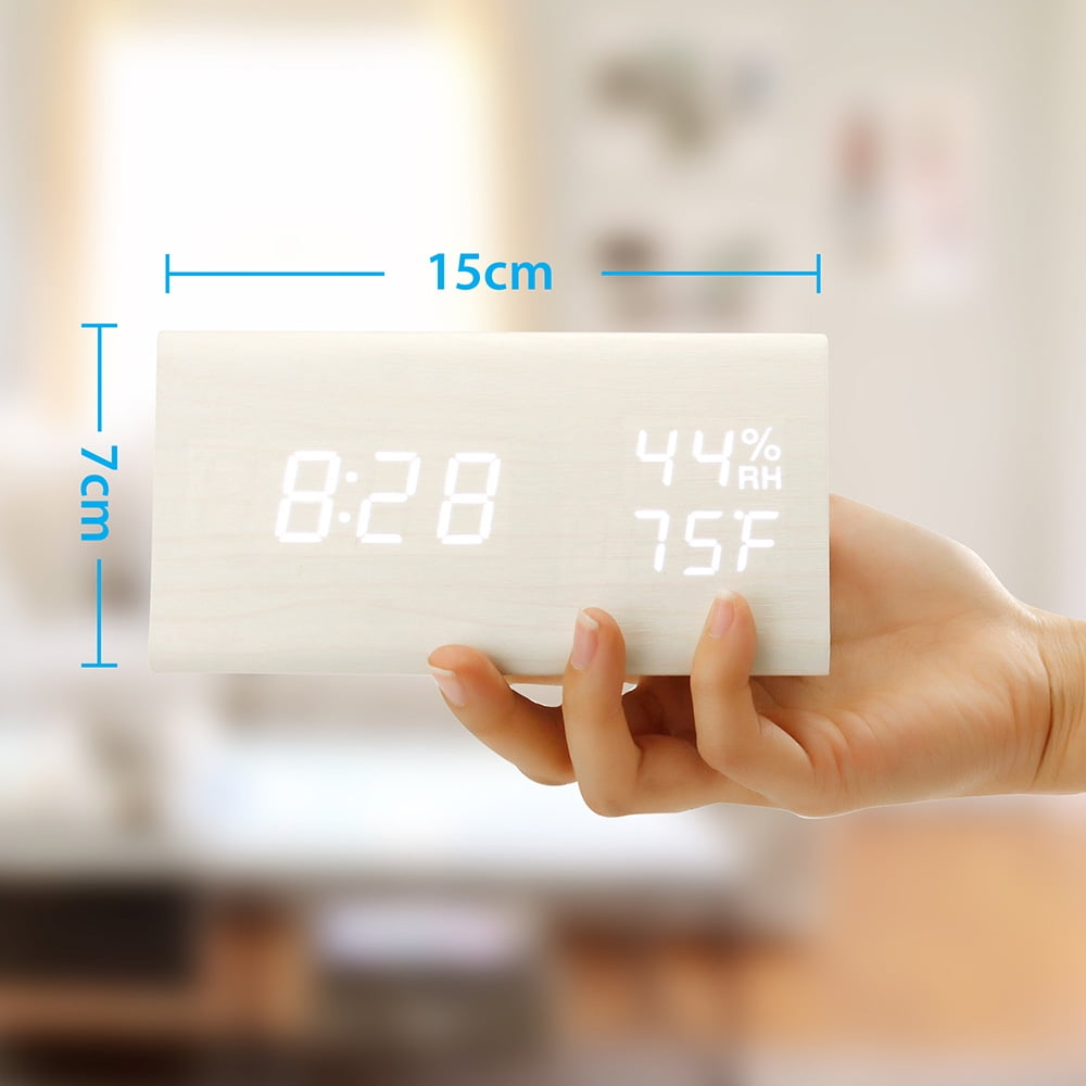 Digitaluhr aus Holz, zeigt Zeit, Temperatur und Luftfeuchtigkeit, gehalten von Hand.