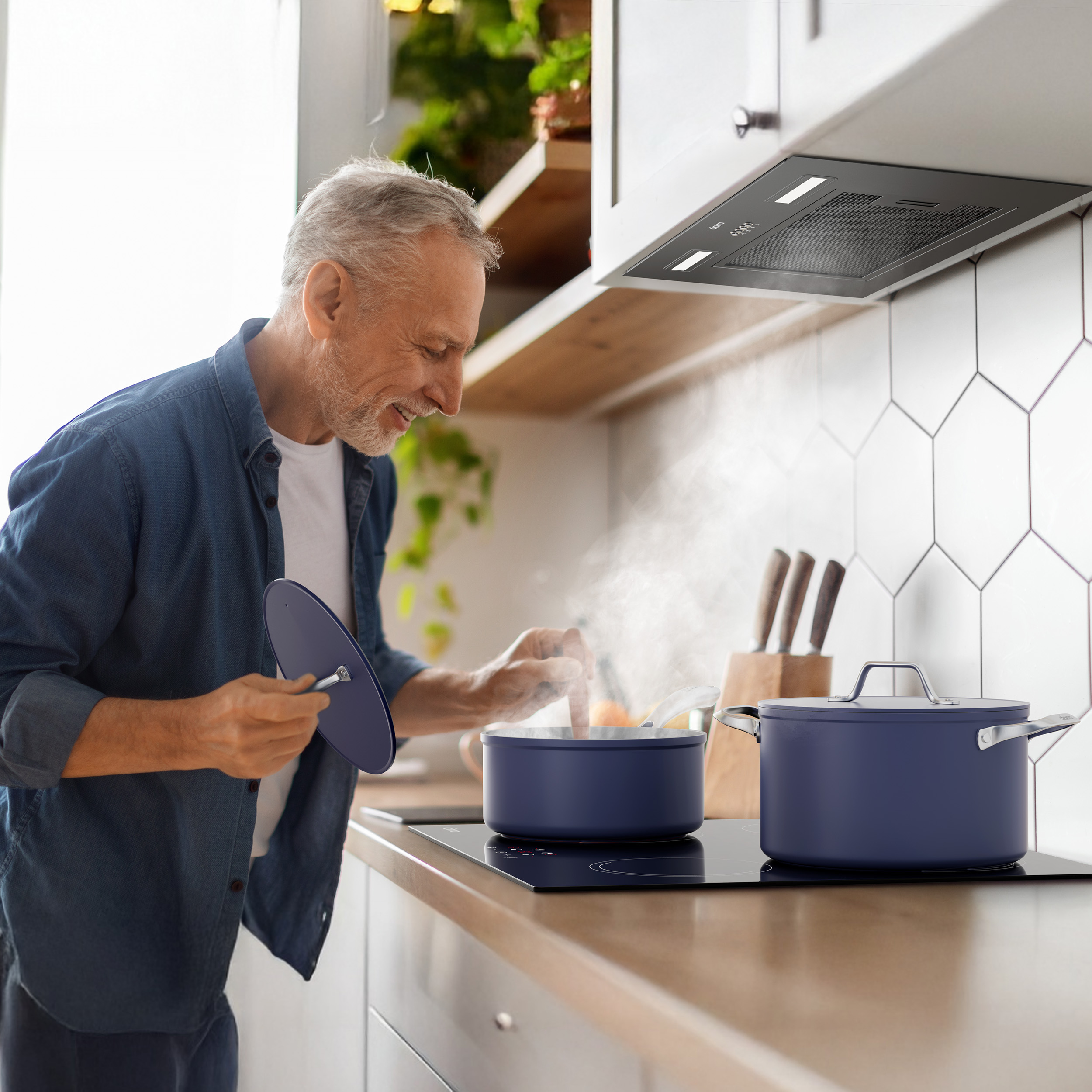 Man kookt met blauwe potten op een inductiekookplaat, stoom stijgt op.