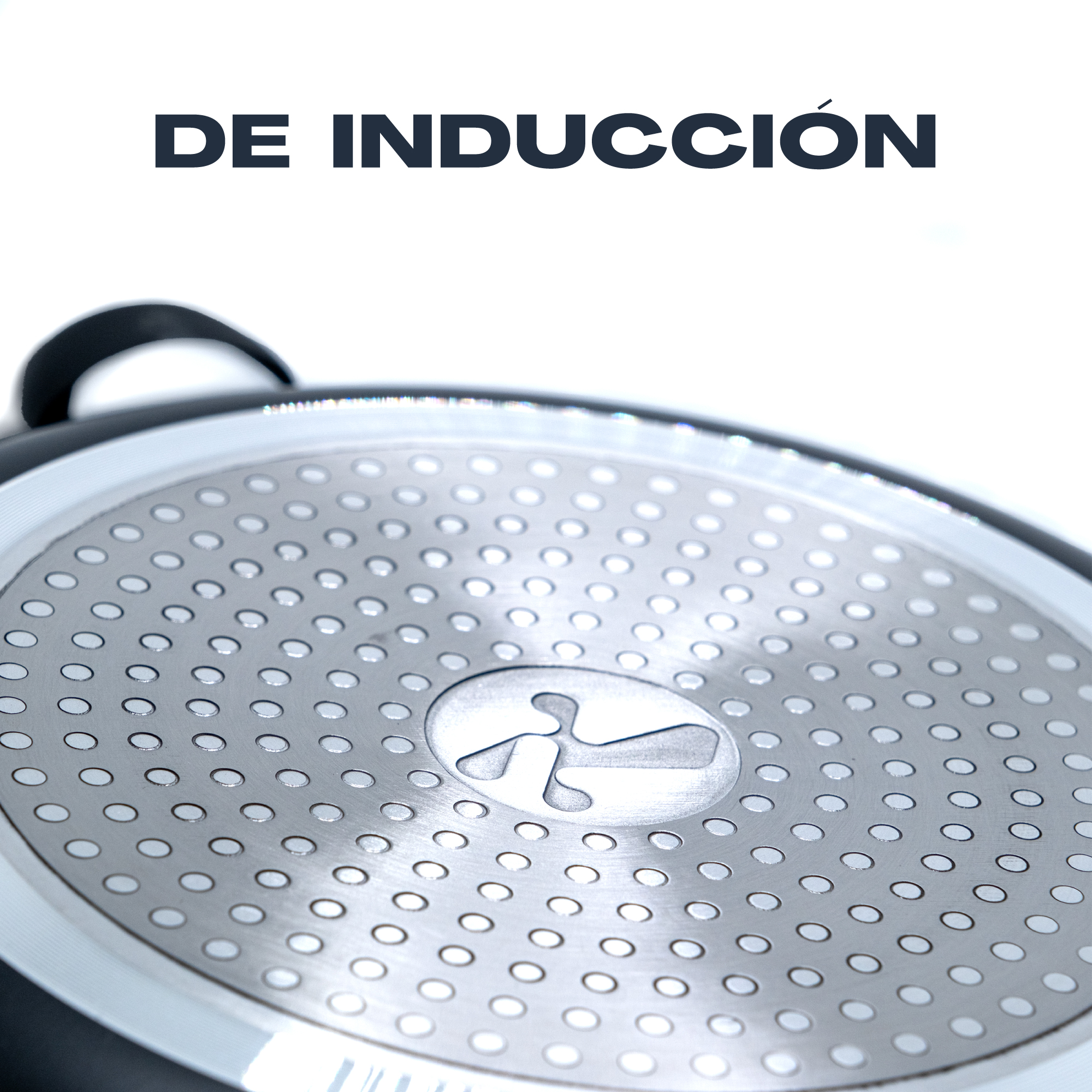 Primer plano del fondo de la sartén de inducción. Metal plateado con patrón de puntos y logotipo central.