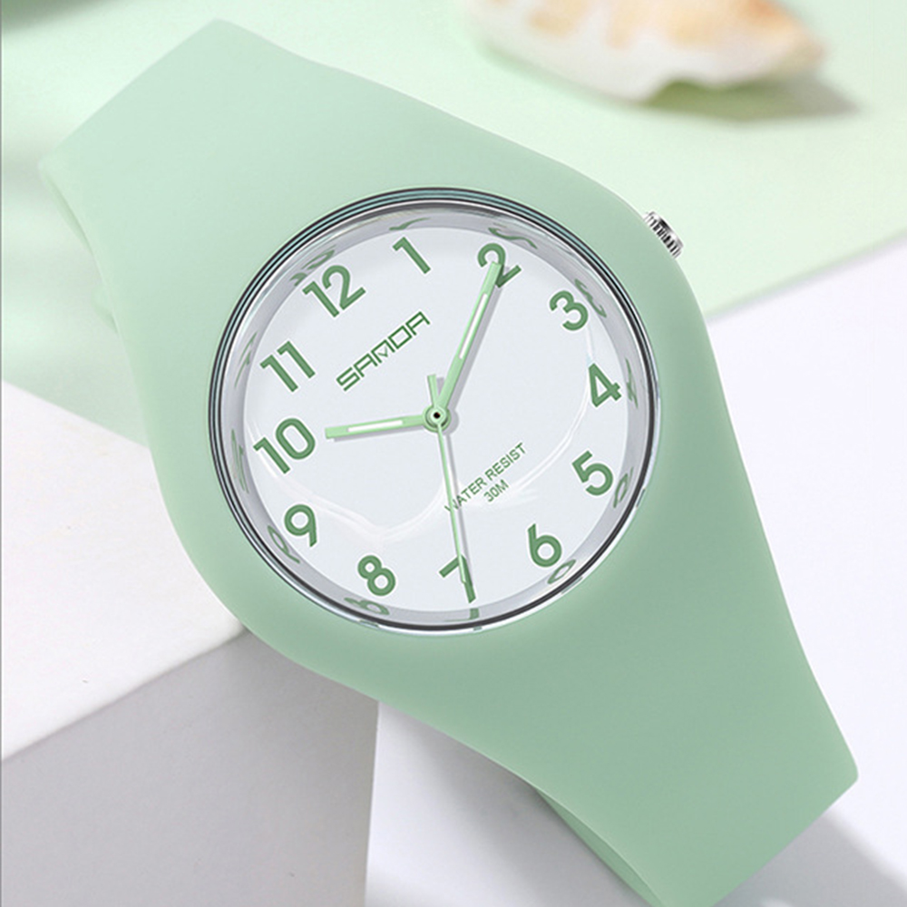 Eine mintgrüne Uhr mit weißem Zifferblatt und grünen Zahlen. Die Uhr liegt auf weißem Untergrund.