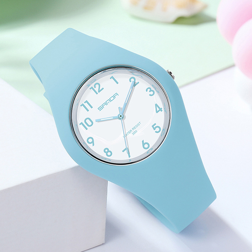 Eine hellblaue Uhr mit weißem Zifferblatt und schwarzen Ziffern auf weißer Oberfläche, hellblaues Armband.