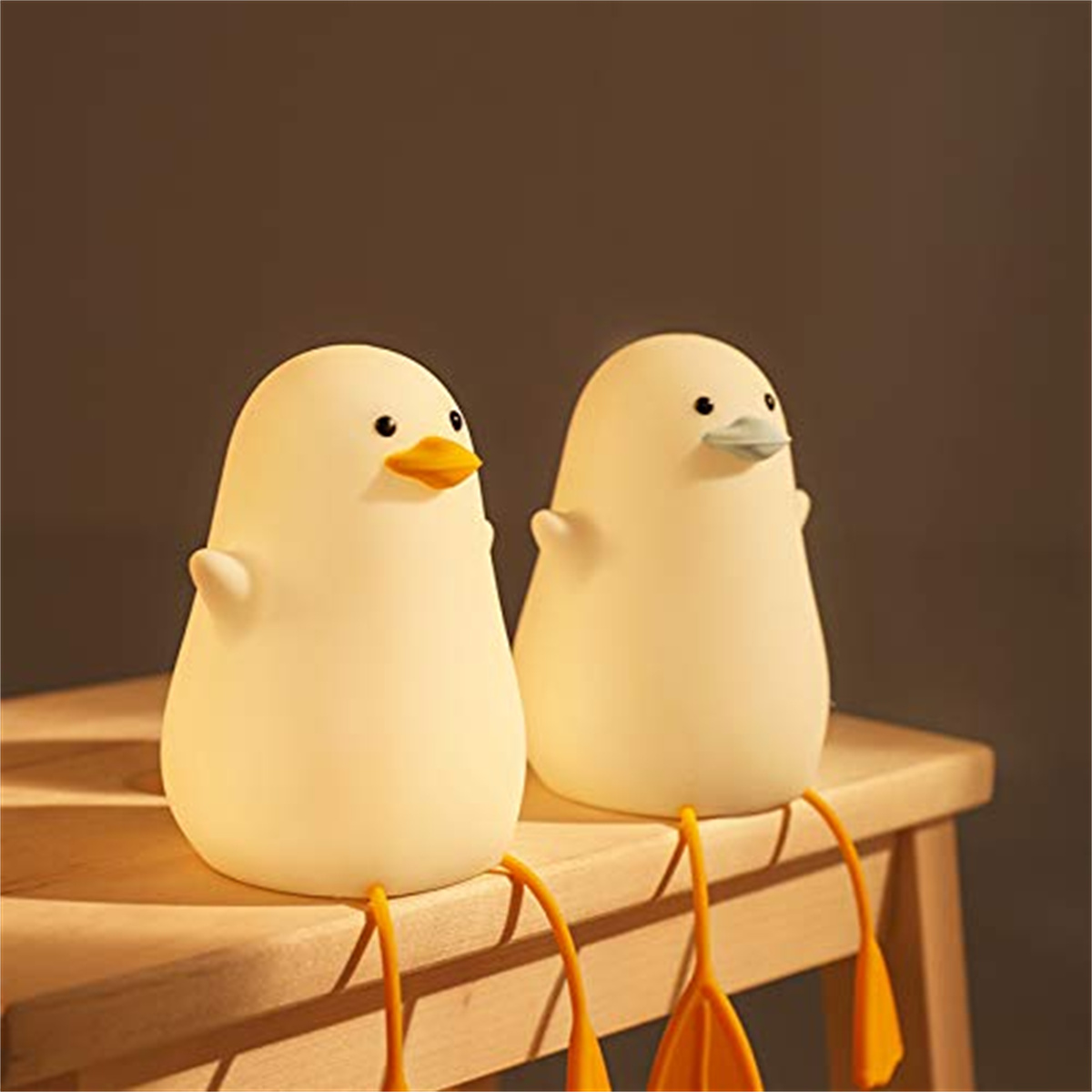 Zwei Enten-förmige Lichter. Sie sind gelb und weiß. Der Hintergrund ist braun.