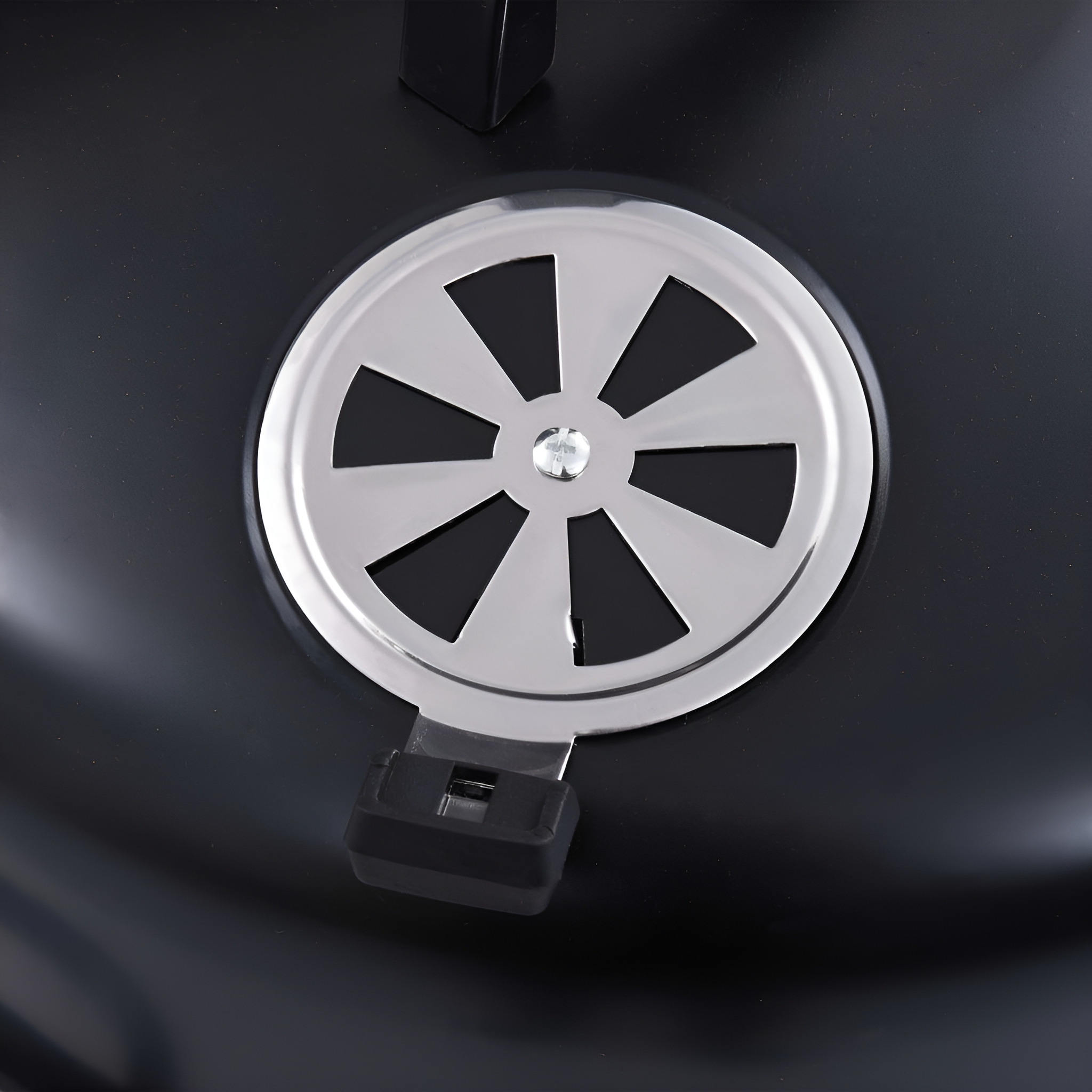 Ventilator mit silberner Lüfterabdeckung auf schwarzer Oberfläche.