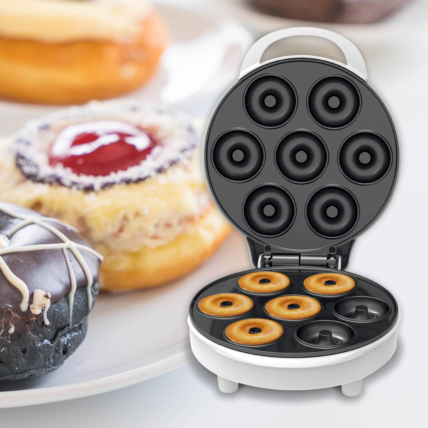 Máquina para hacer donas con donas y donas en plato. Se están haciendo siete donas.