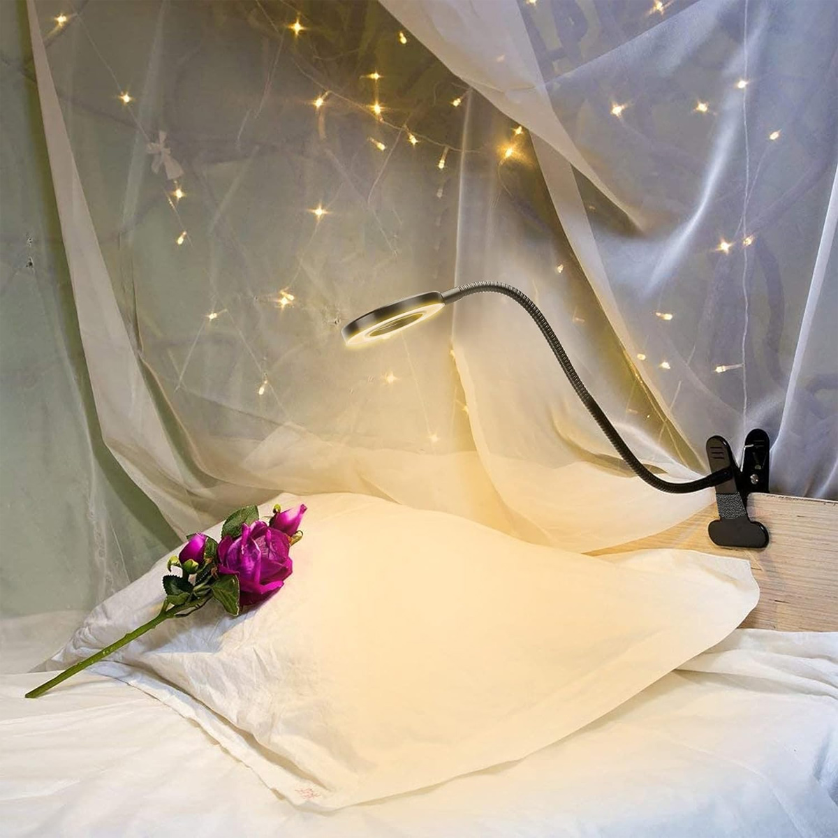 Eine flexible Schreibtischlampe mit Licht, Rose und Kissen. Die Lampe ist eingeschaltet.