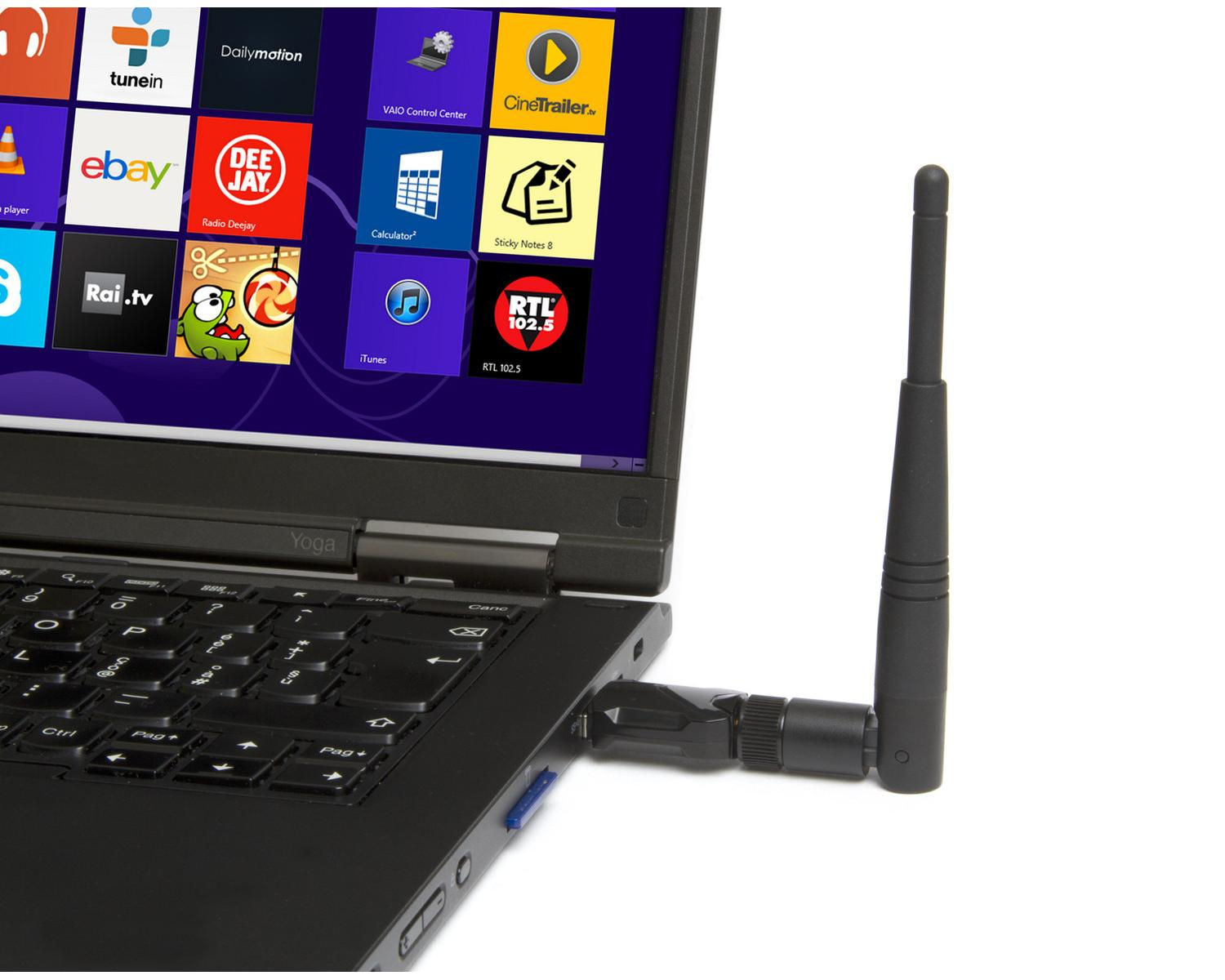 Laptop z podłączoną anteną. Ekran pokazuje wiele ikon aplikacji. Białe tło.