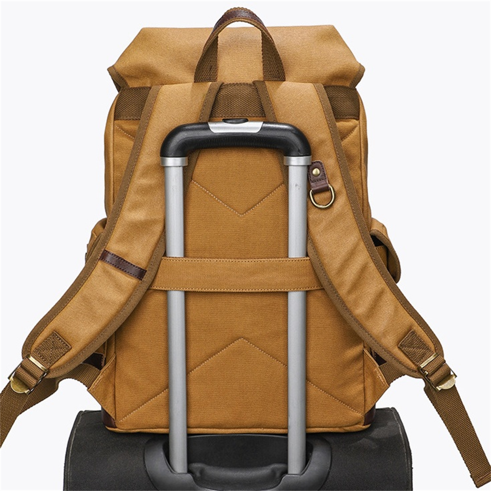 Die Rückseite eines braunen Rucksacks auf einem Rollkoffer. Die Träger und der Griff sind sichtbar.